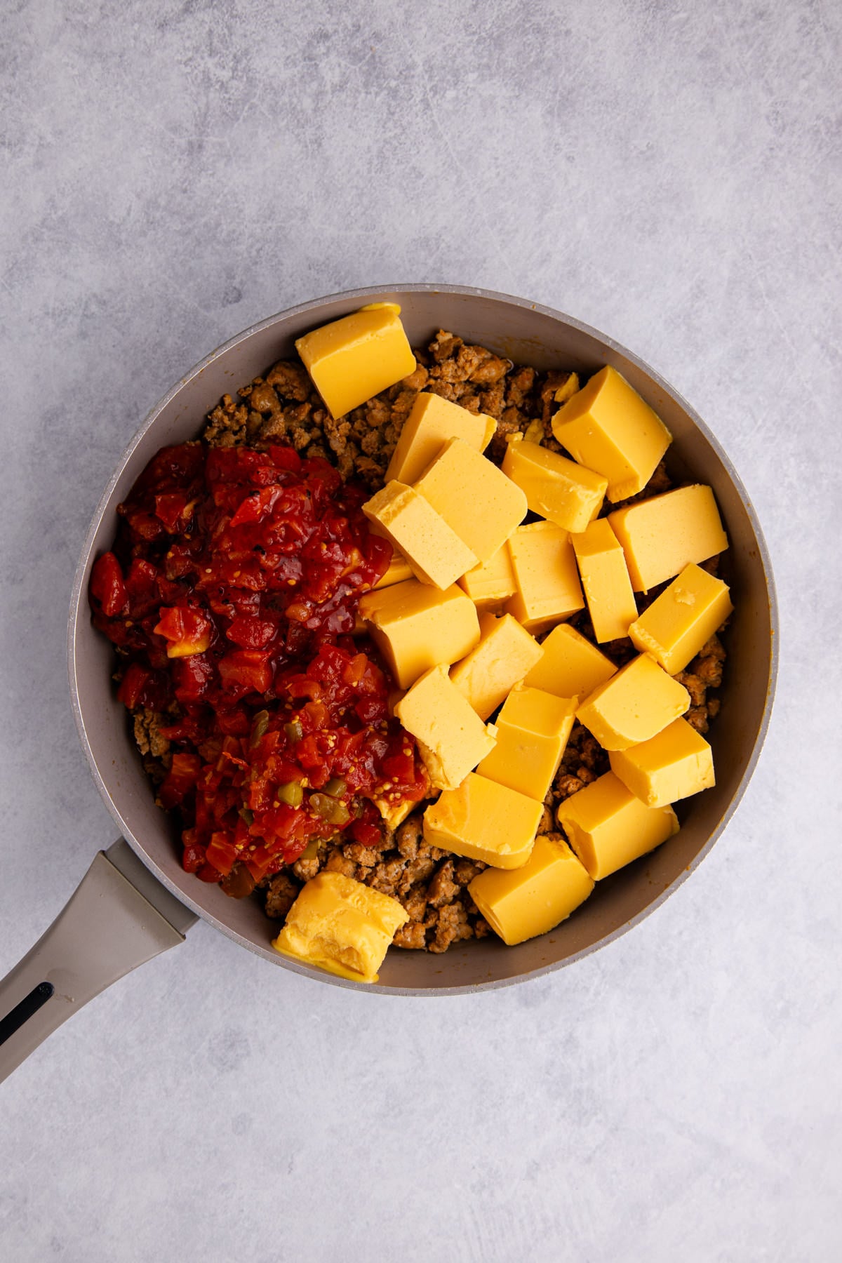 Velveeta and tomatoes added to the ground sausage.