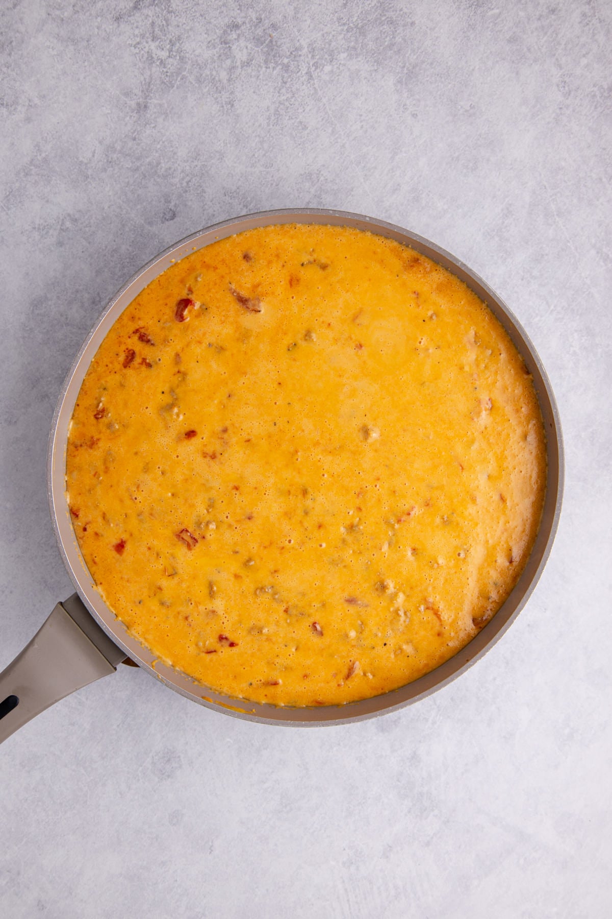 Melted sausage queso with velveeta in a pan.