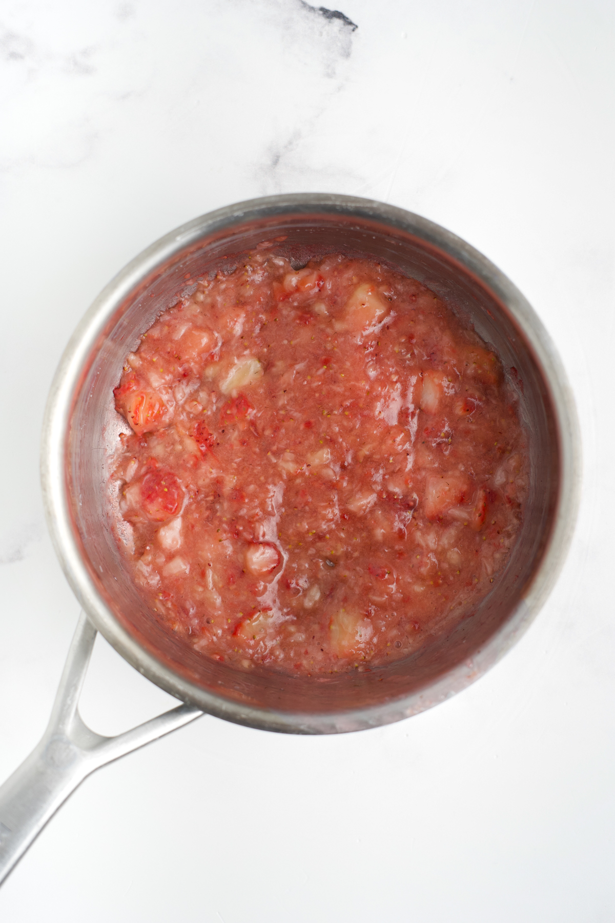 Strawberry swirl mixture heating in a saucepan.