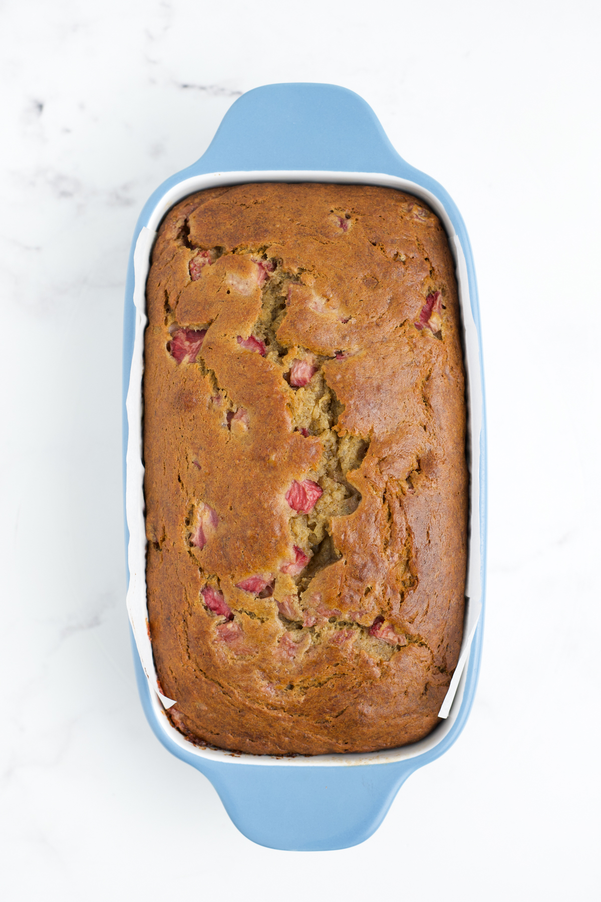 A baked strawberry banana bread cooling in the loaf pan.