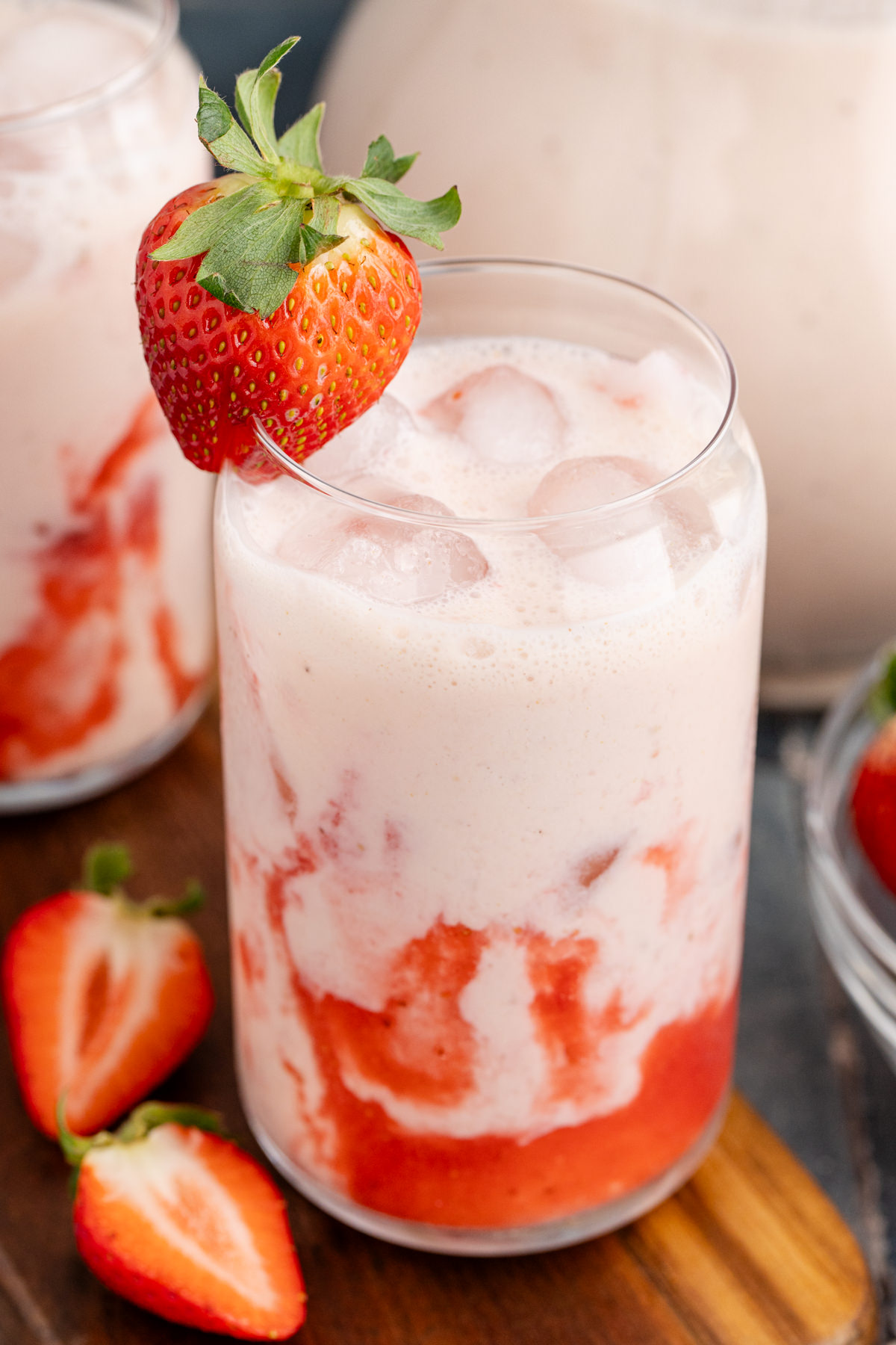 A glass filled with strawberry horchata and a strawberry garnish on top.