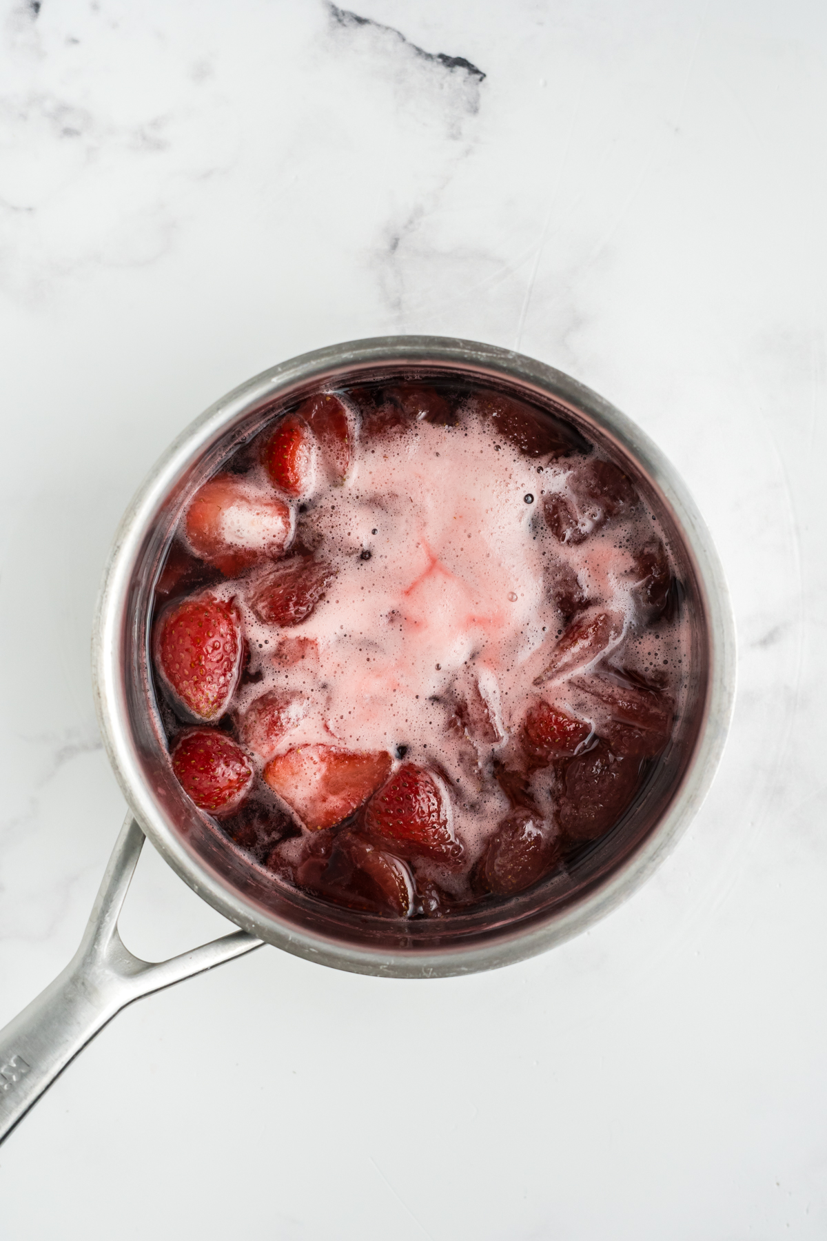 Strawberries, sugar, and water in a saucepan.
