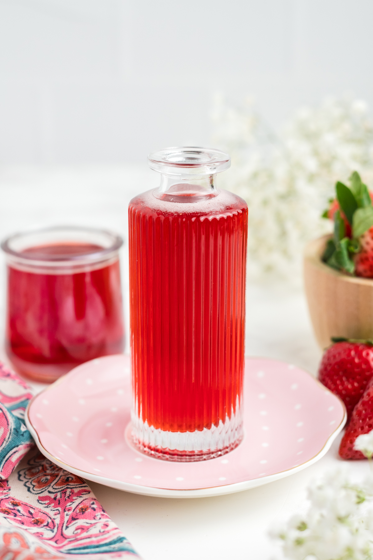 Strawberry syrup in a bottle on a pink plate. 