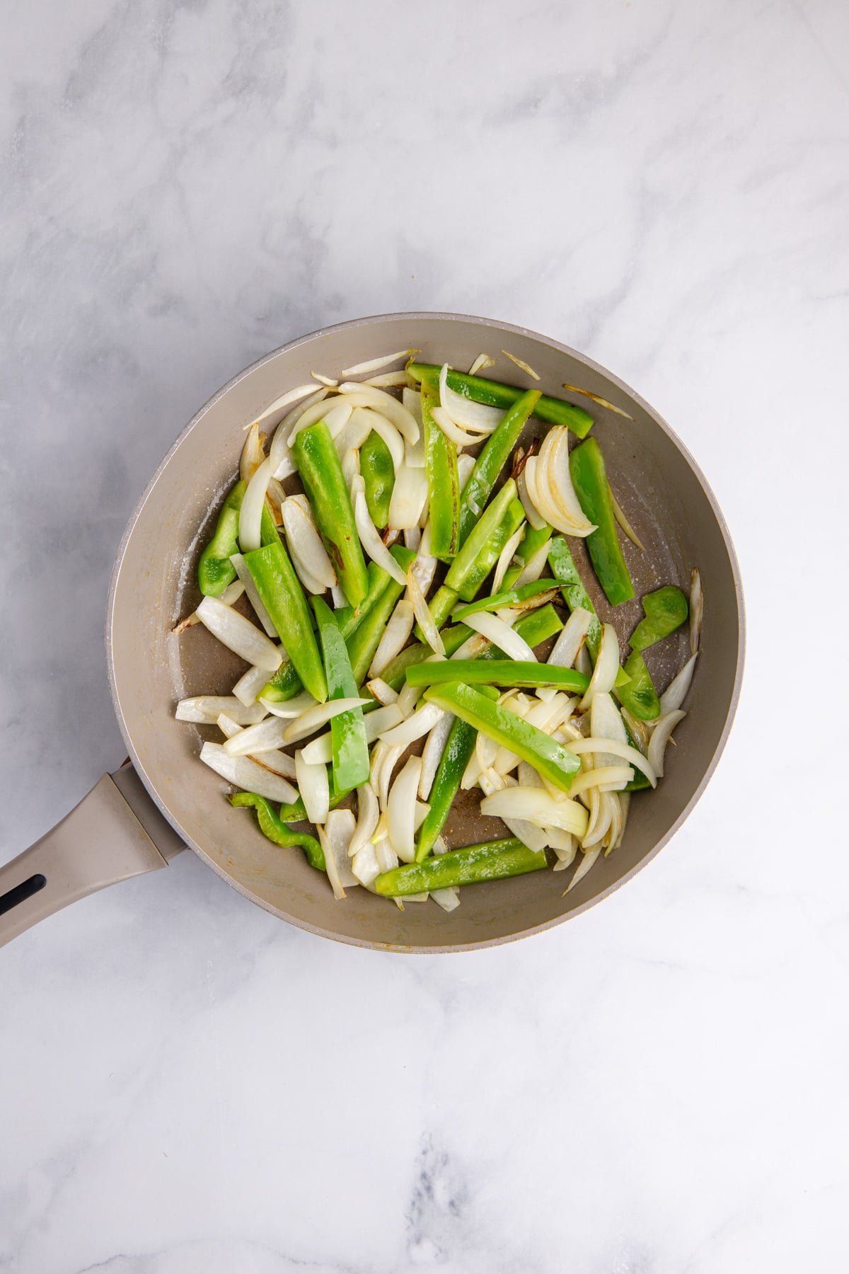 Peppers and onions cooking in a skillet.