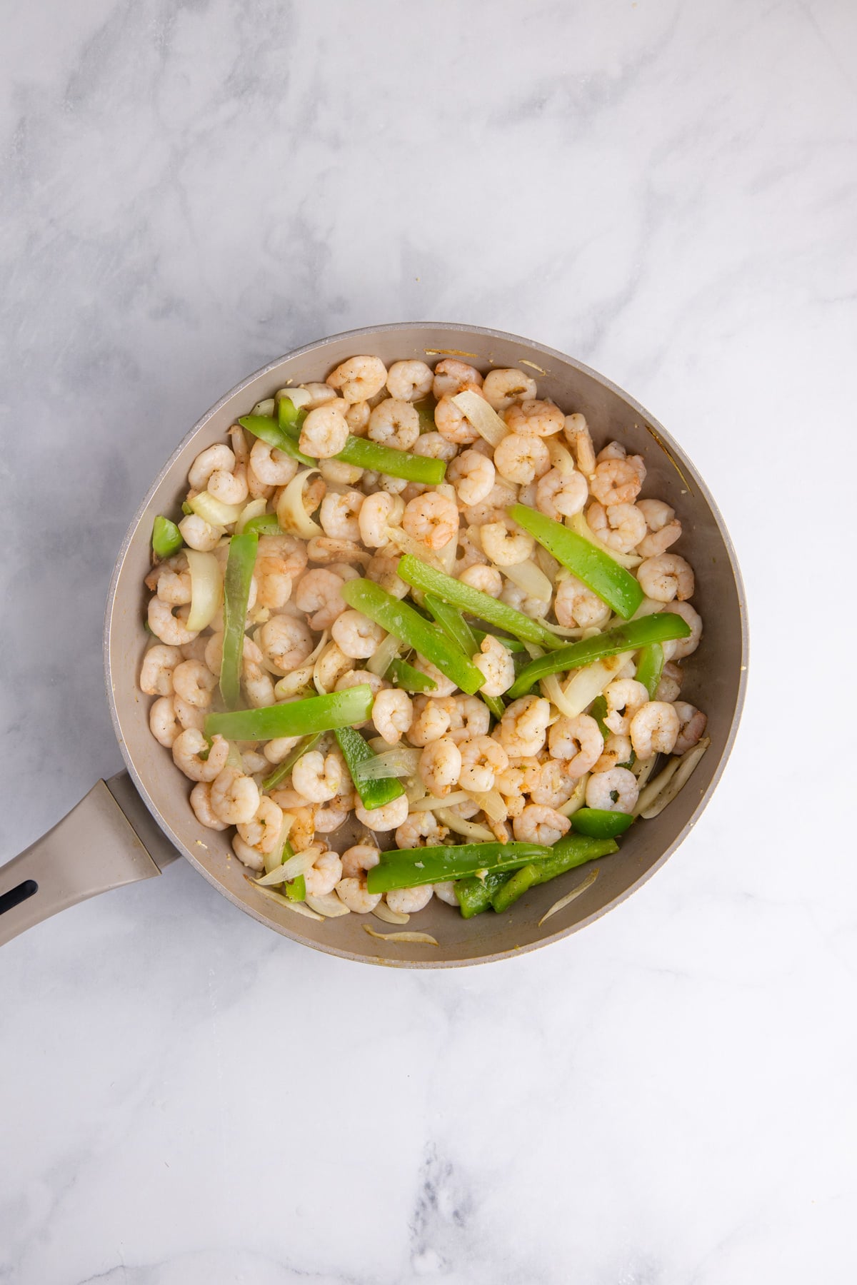 Shrimp, garlic, and seasoning added to the skillet.