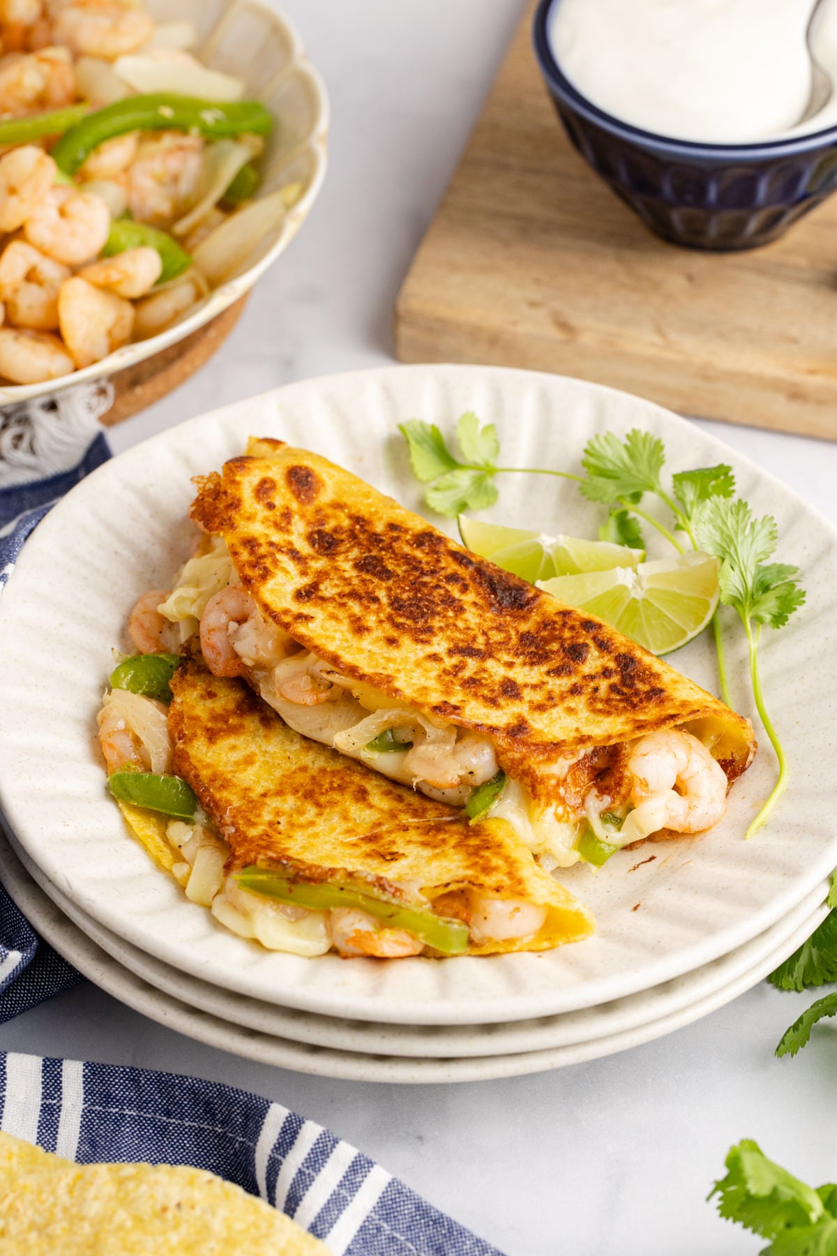 Two shrimp tacos on a plate with lime and cilantro on the side.