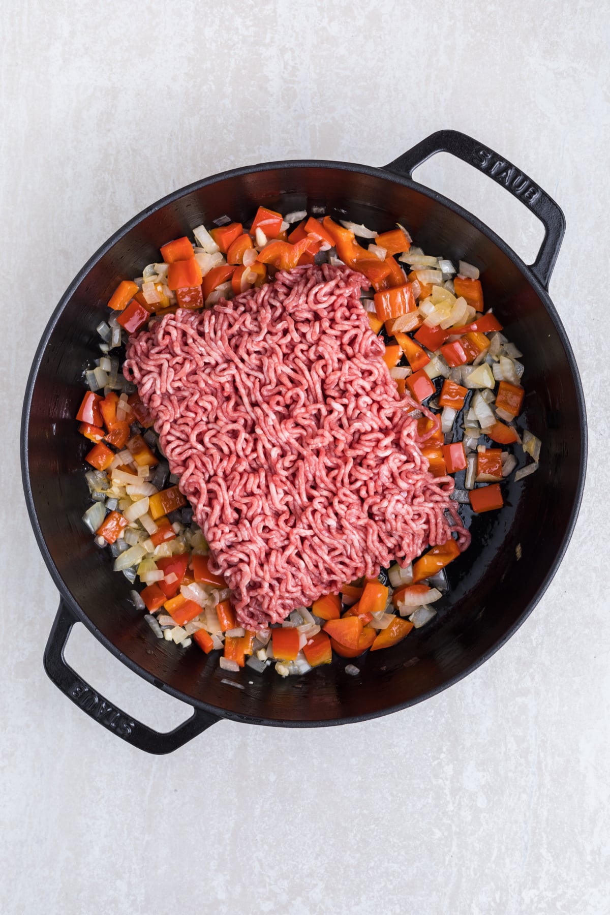 Ground beef, onions, and bell pepper cooking in a skillet.