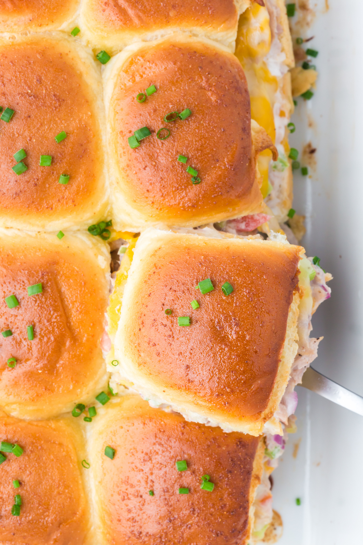 The baked sliders with one being removed.