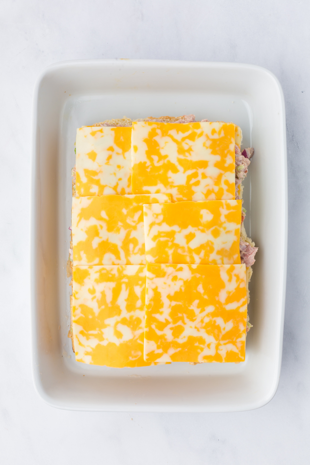 SLiders with a layer of cheese slices, tuna and a final layer of cheese.