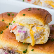 A tuna melt slider on top of the dish full of freshly baked sliders