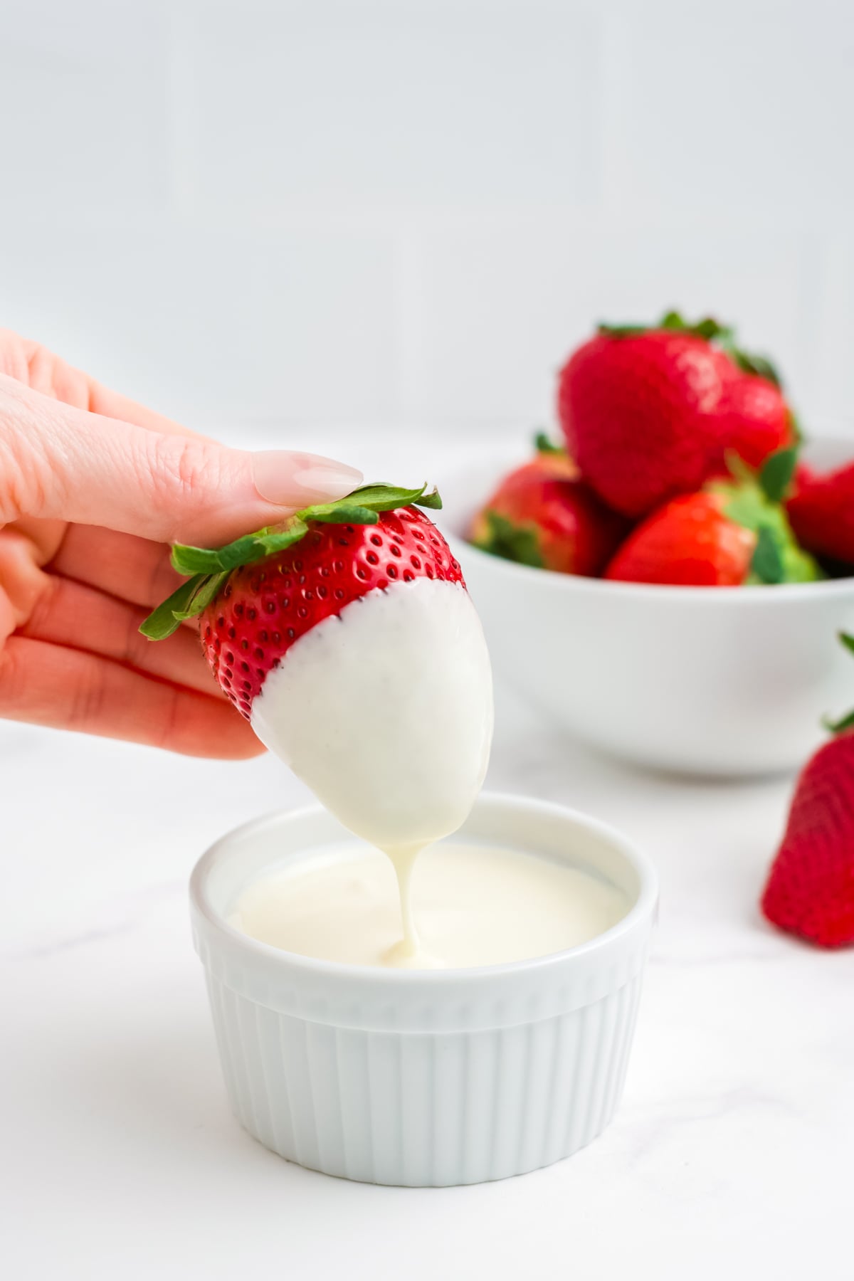 A strawberry being dipped into white chocolate.