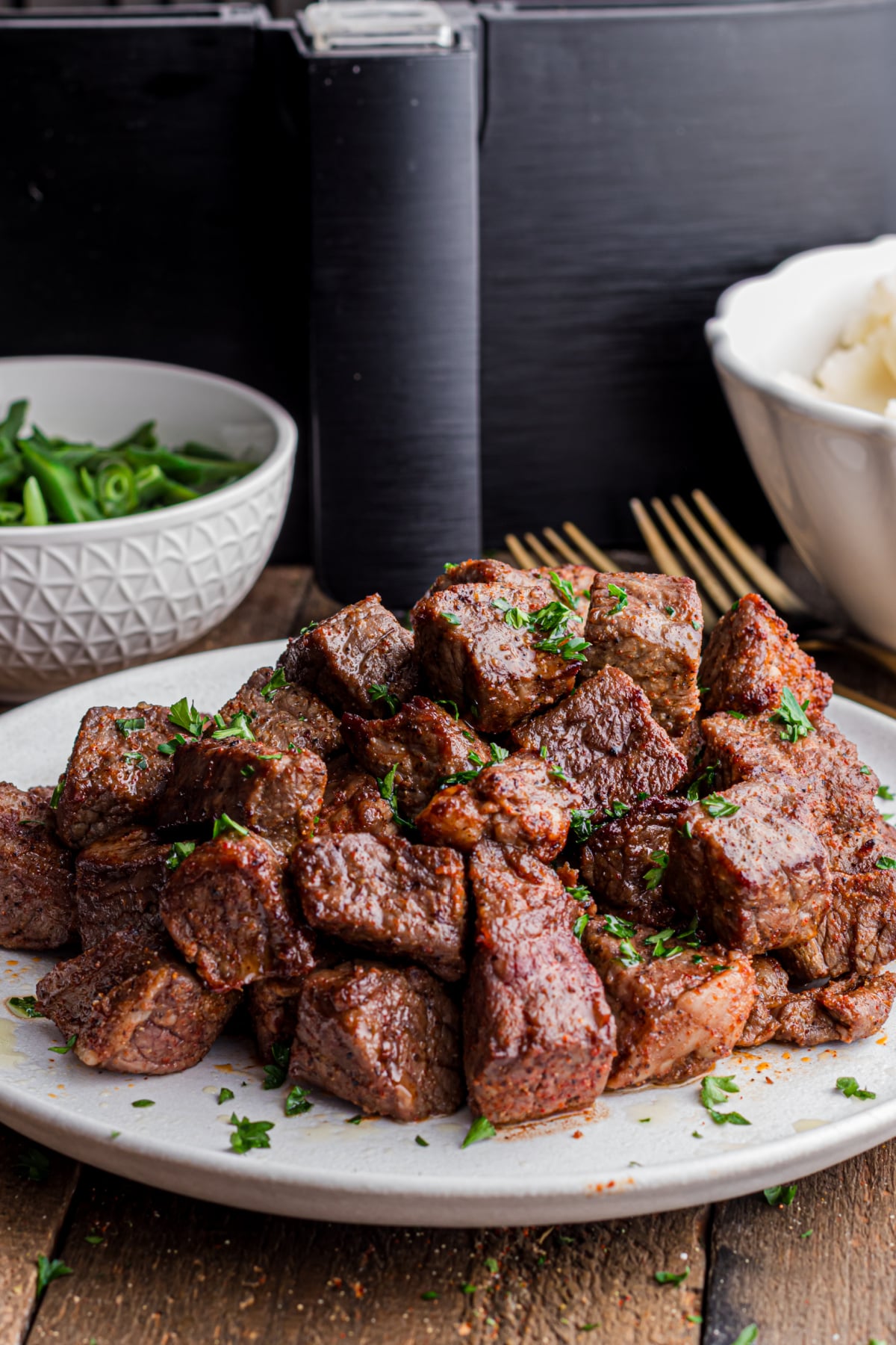A plate full of steak bites on a serving plate on a table.