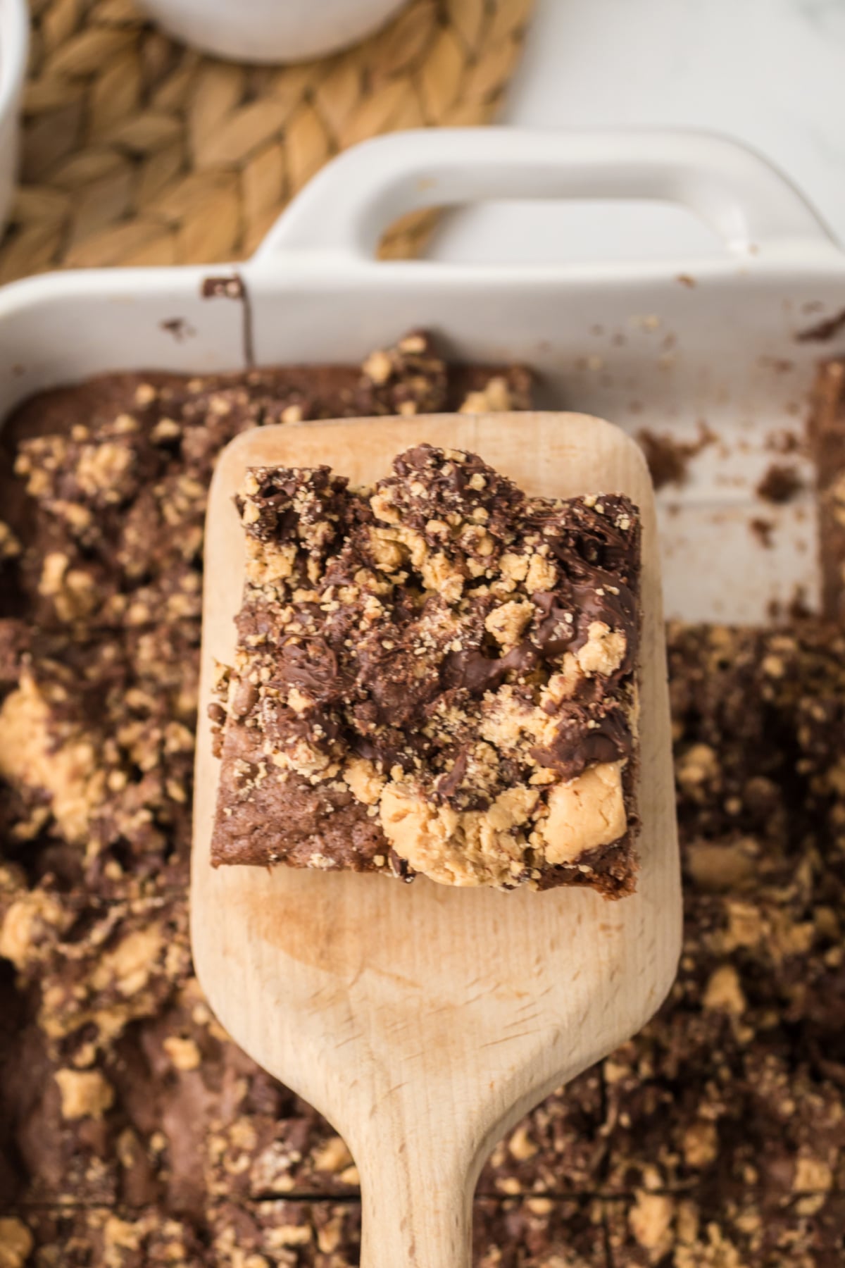 A brownie on a spatula lifted out of the ban above the pan of brownies.