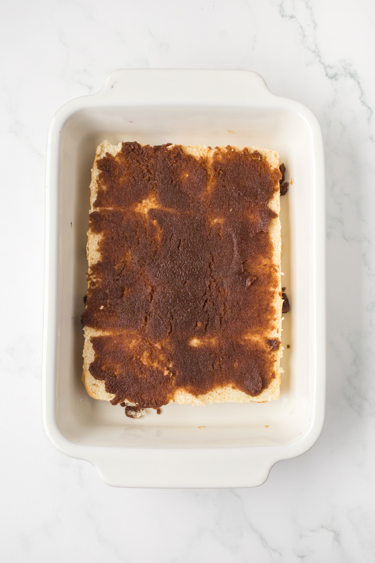 Bottom half of King's Hawaiian Cinnamon Rolls in baking dish covered in cinnamon mixture.