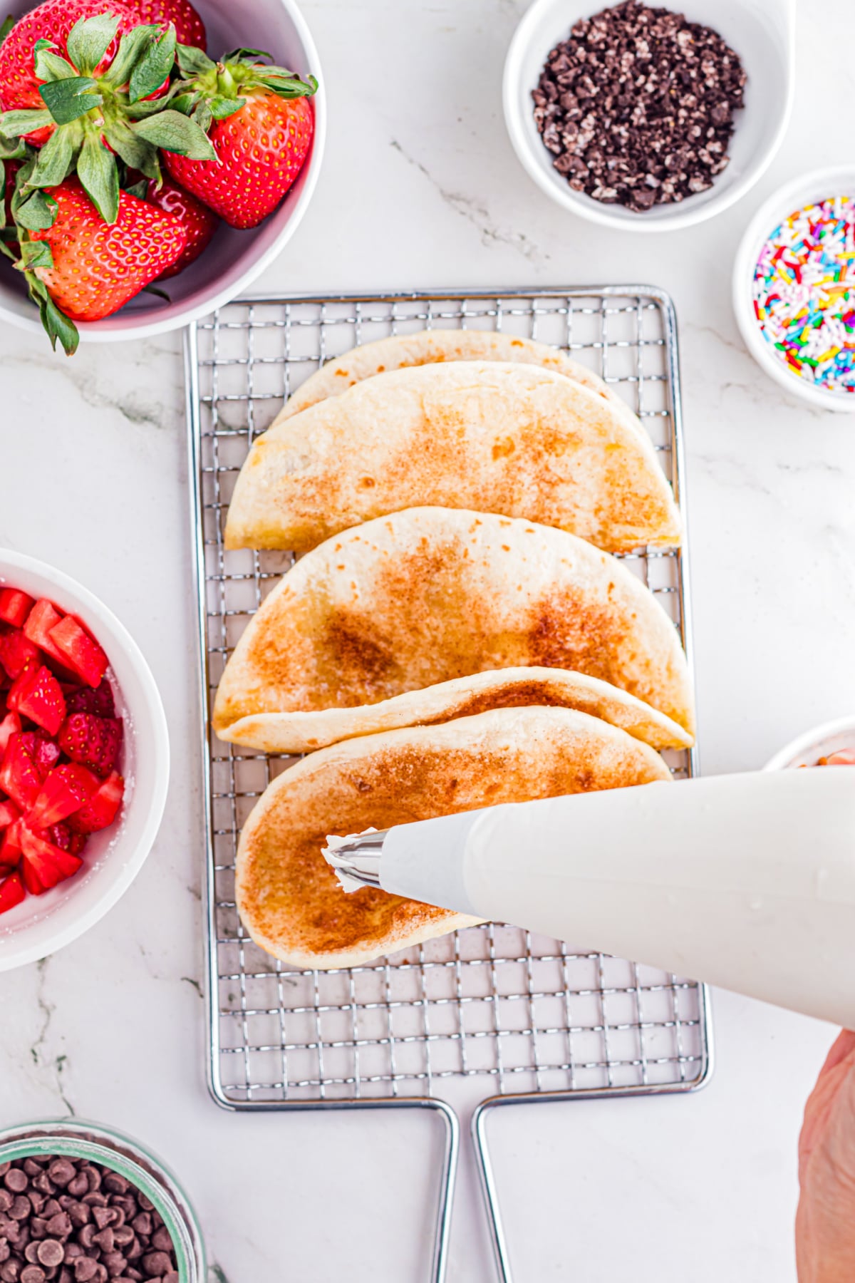 Tacos being filled with cream filling.