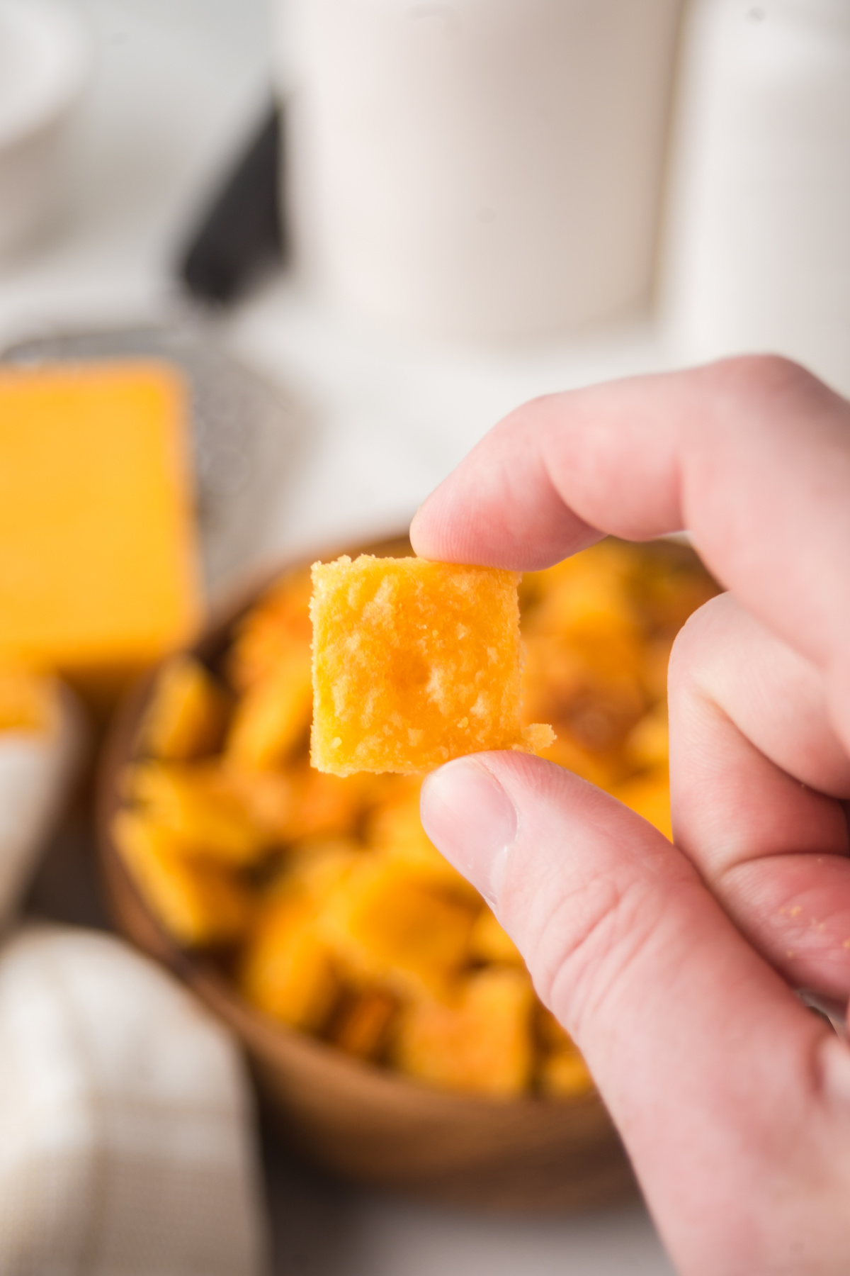 A homemade cheez it being held up in the air.