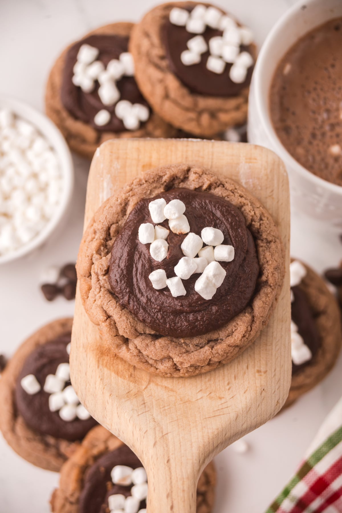 A wooden spatula holding up a cookie with chocolate in the center.