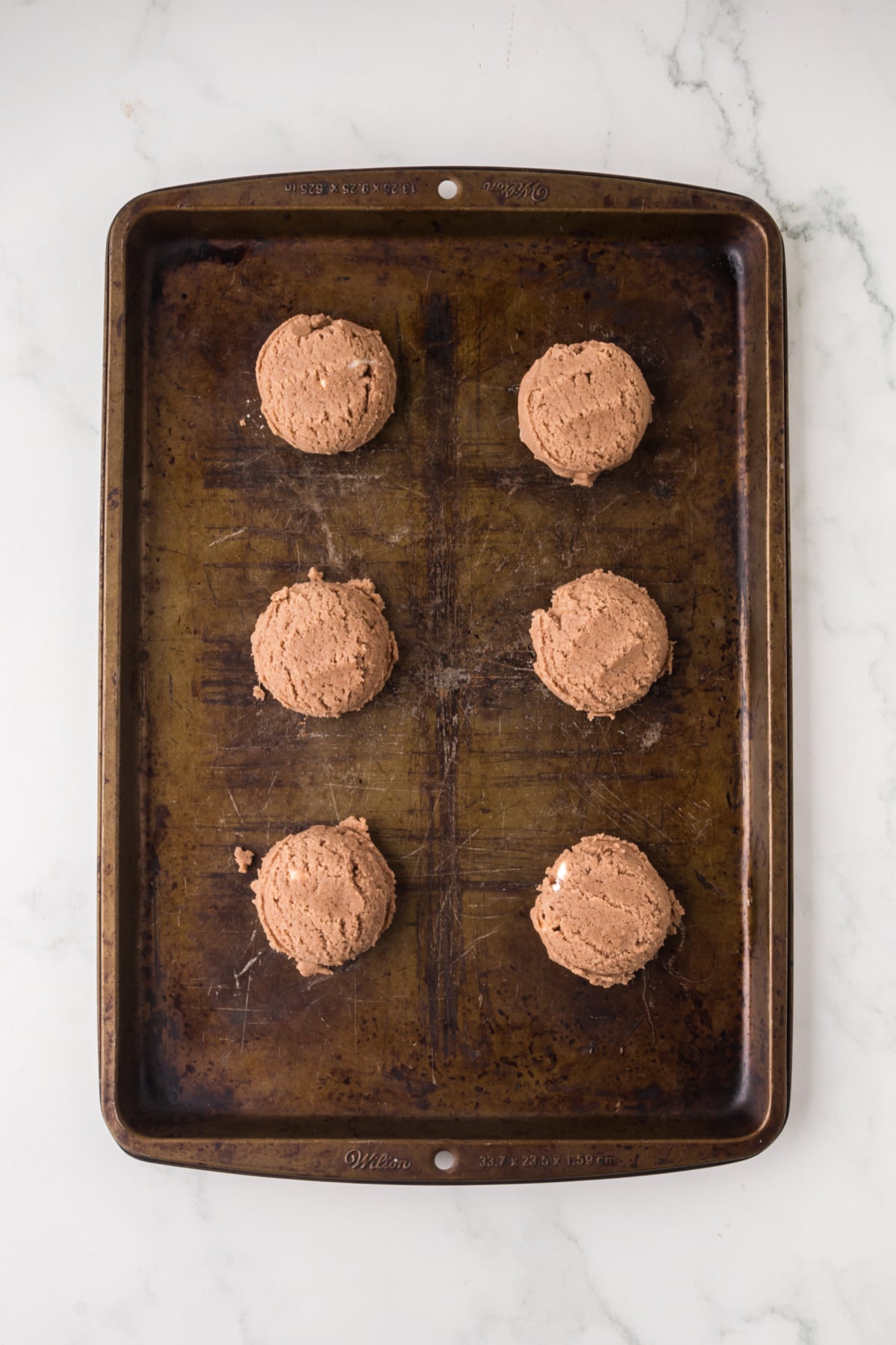 Cookie dough scooped onto a baking sheet.