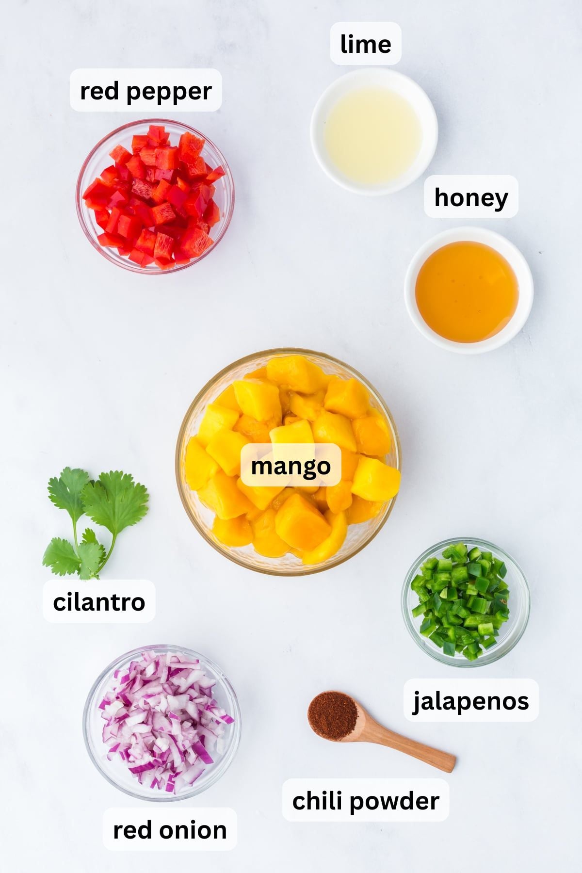 Ingredients to make Mango Salad in bowls on a table