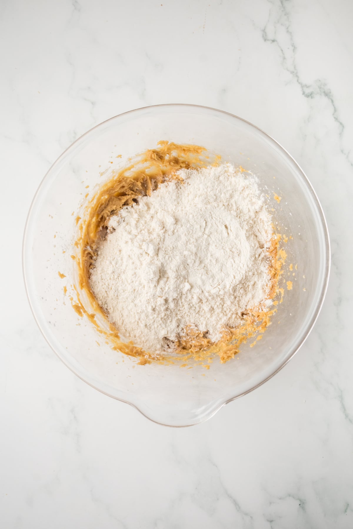 adding flour to peanut butter cobbler dough in bowl