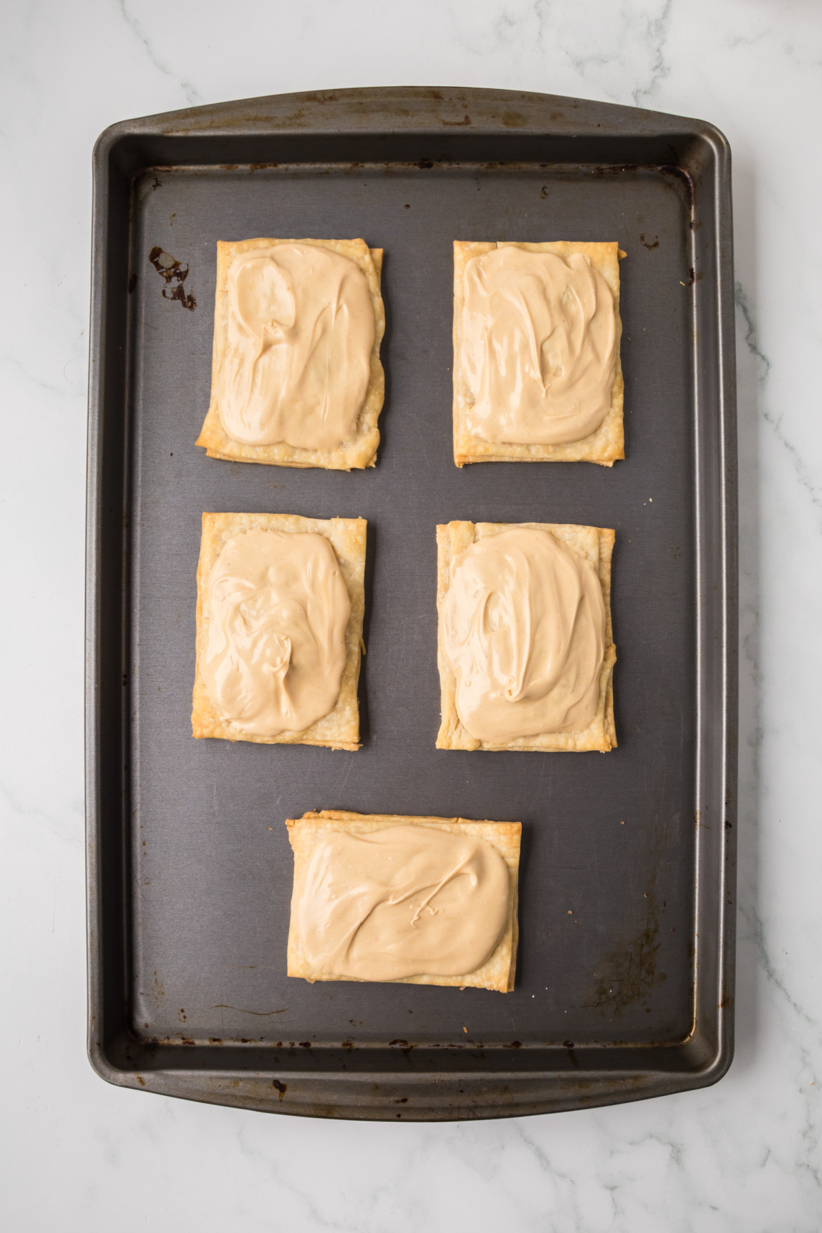 Cooled baked pop tarts on pan with glaze.