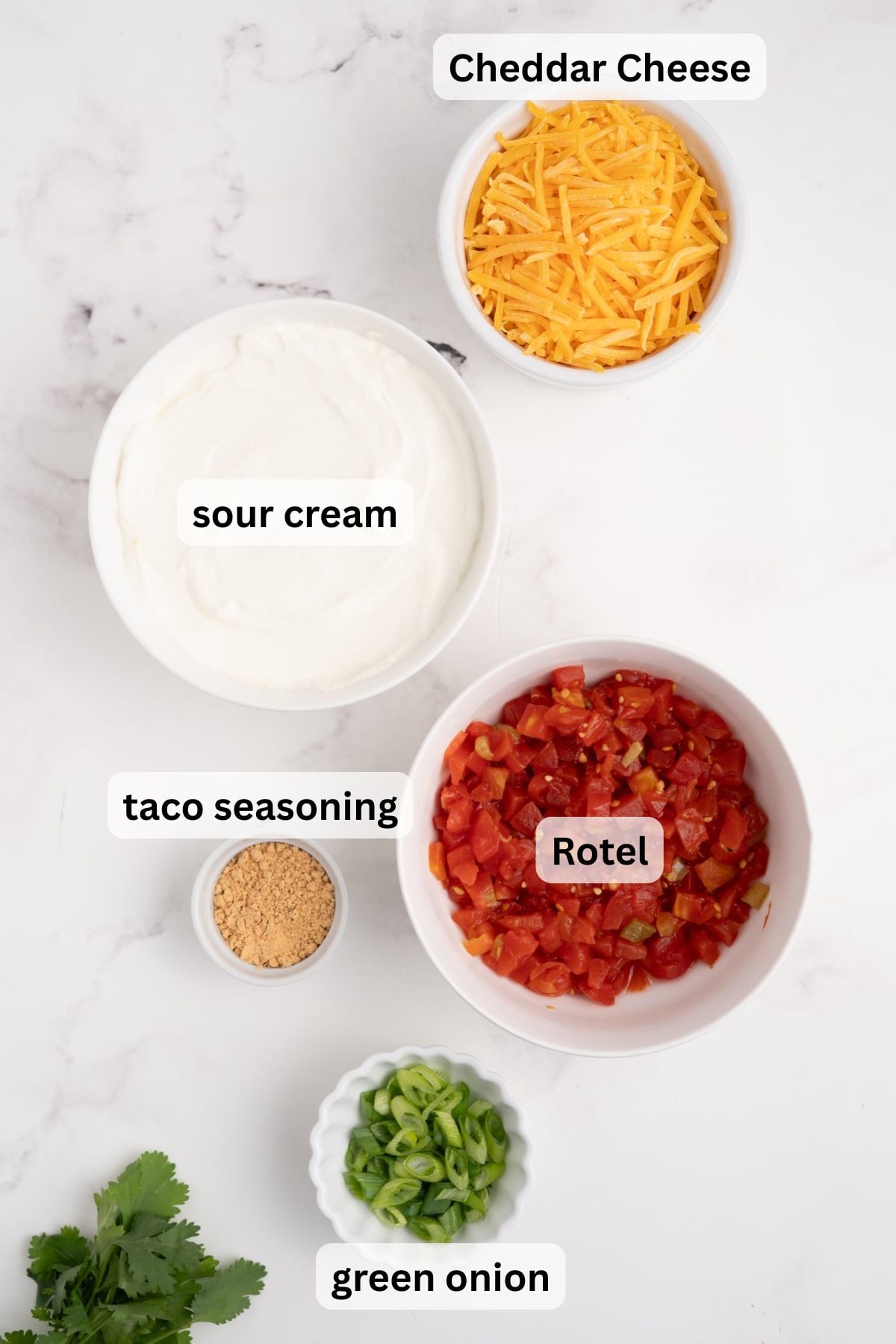 Ingredients to make taco boat dip in bowls on a table.
