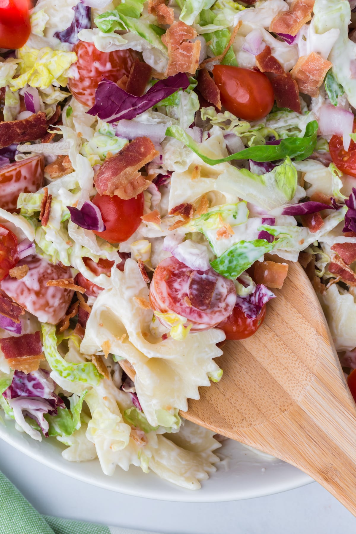A wooden spoon lifting a spoonful of salad out of a bowl