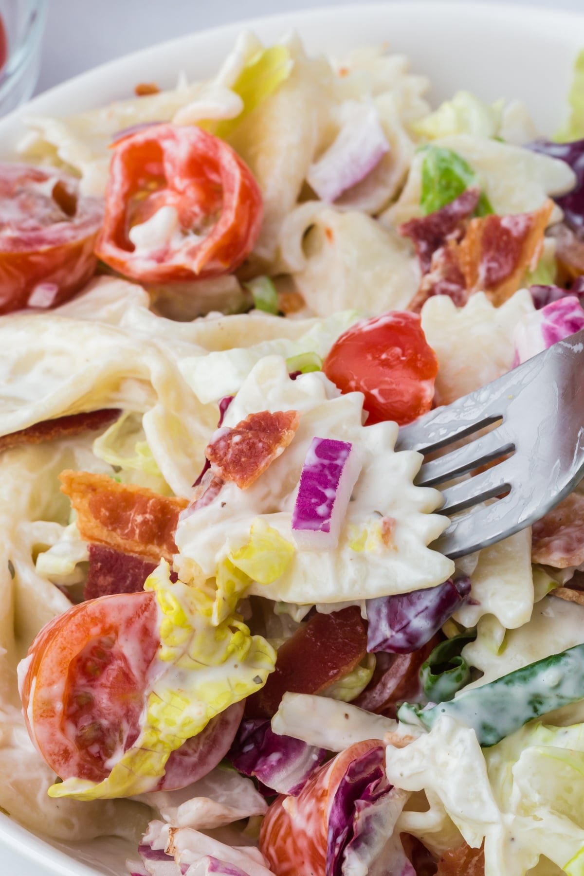 A fork removing a bite of pasta salad from a bowl