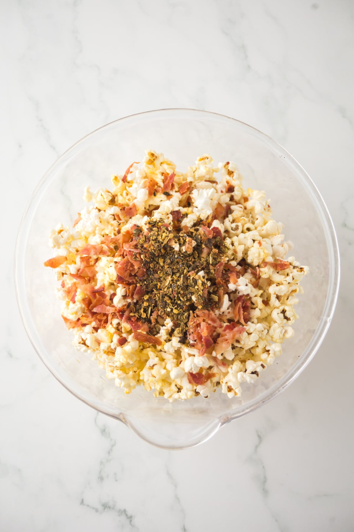 Popcorn in a bowl with ingredients on top.