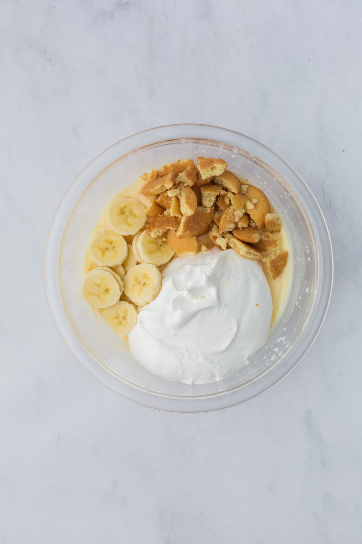 adding bananas, whipped topping and wafers to the bowl of fluff