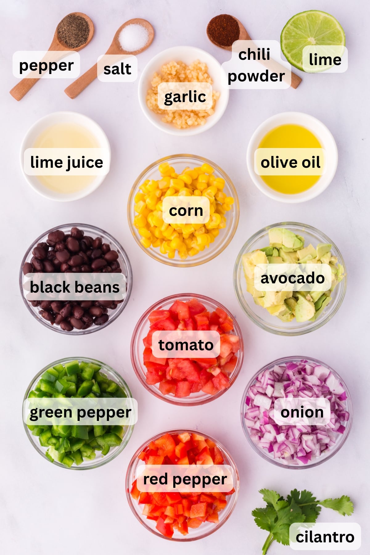 All of the ingredients needed to make Black Bean and Corn Salad in bowls on a table.
