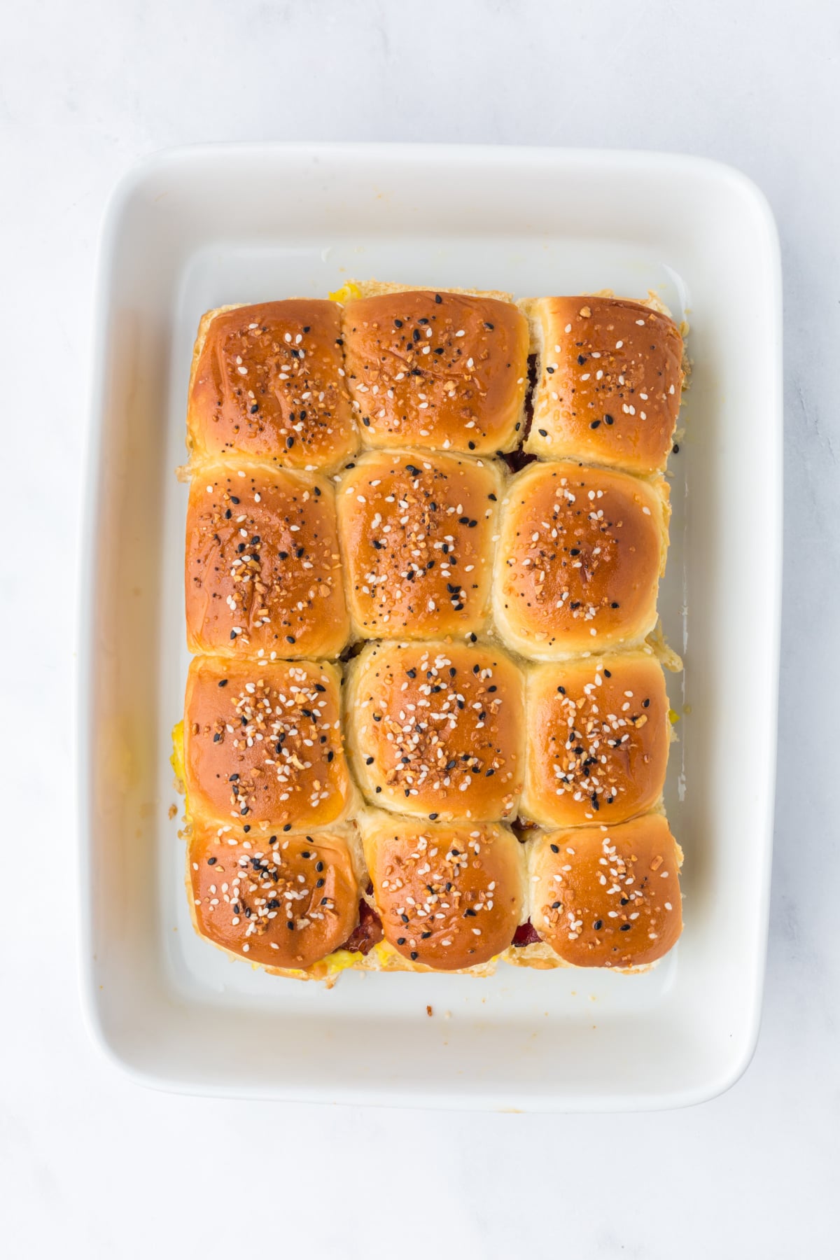 placing top buns and brushing butter mixture over breakfast sliders and baking them