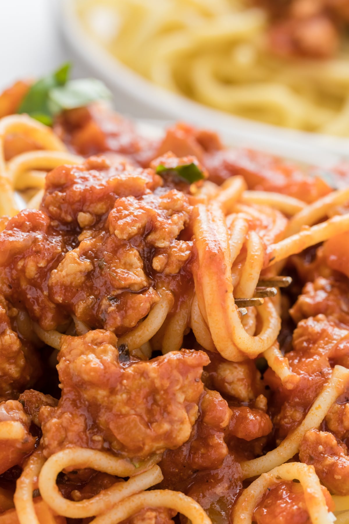 A fork twirling some bolognese with chicken.