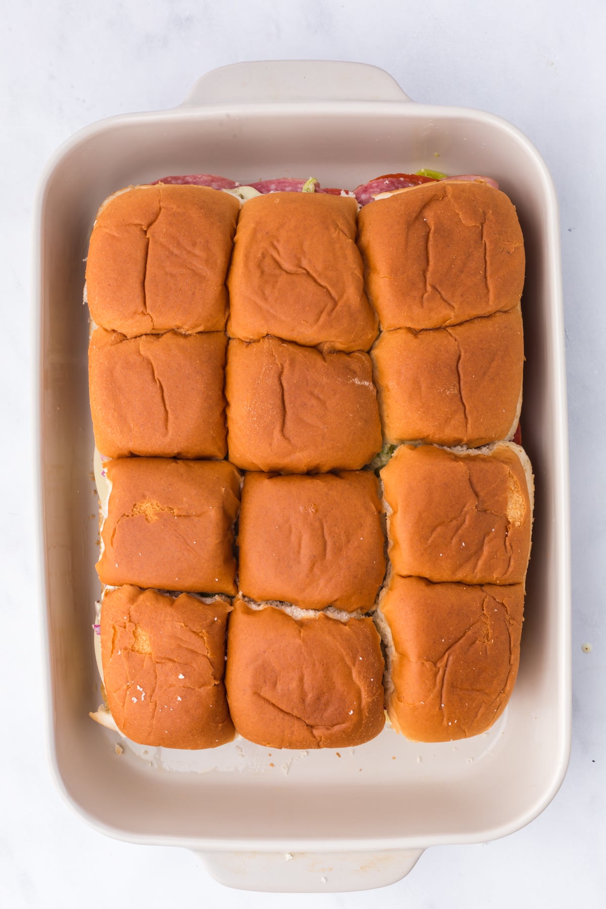 Tops placed on sliders ready to be brushed with butter and a sprinkling of italian seasoning on top