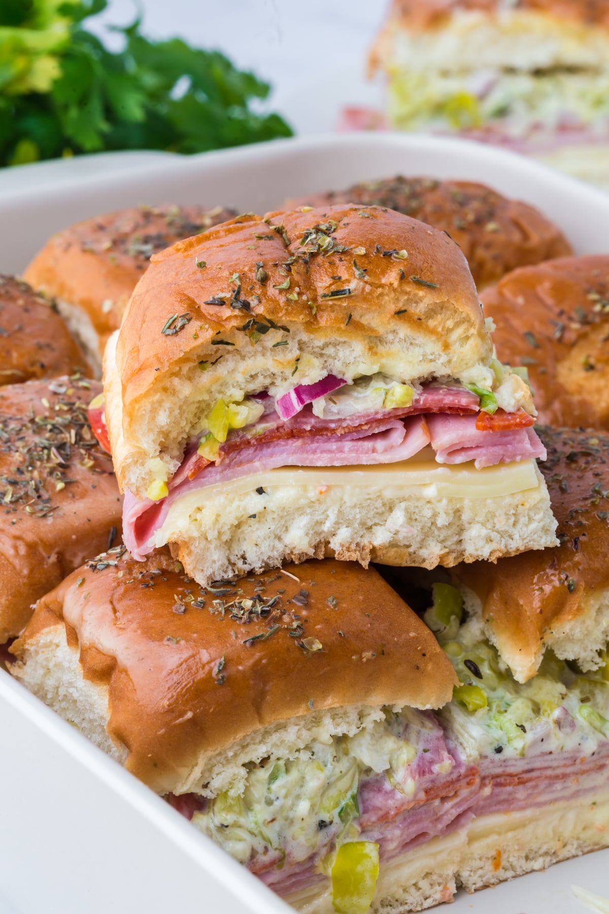 A chopped Italian slider on top of others in baking dish
