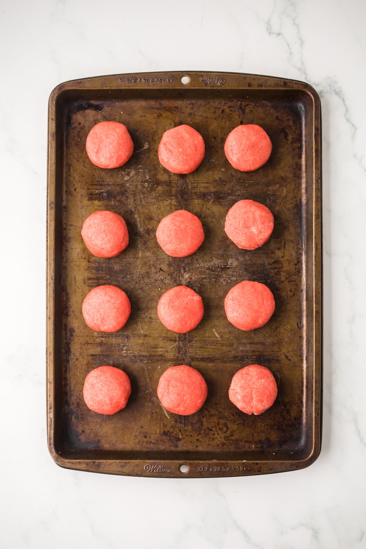 scooping cookie dough onto baking sheet for hershey kiss cookies