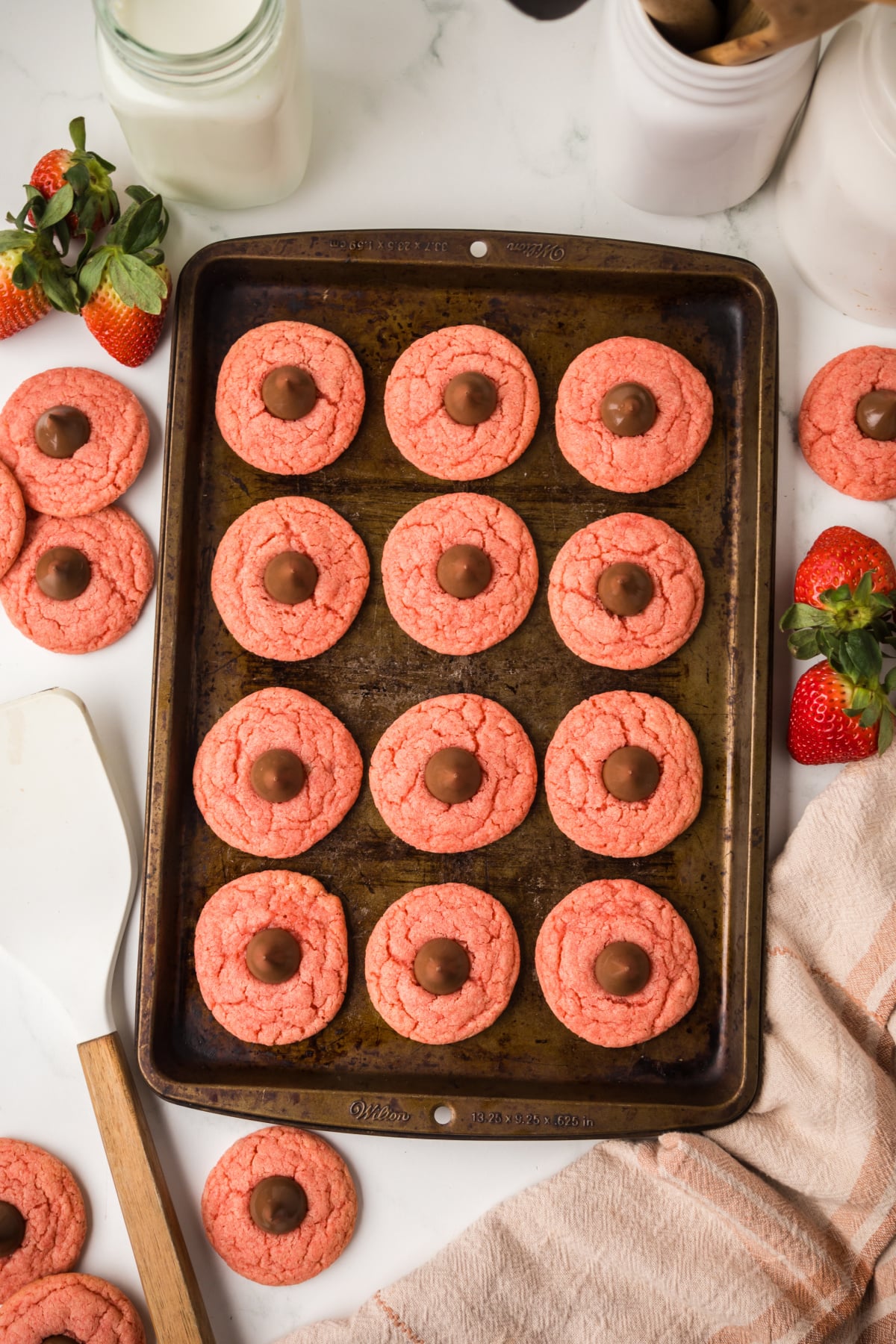 pressing hershey kiss into warm cookie after baking