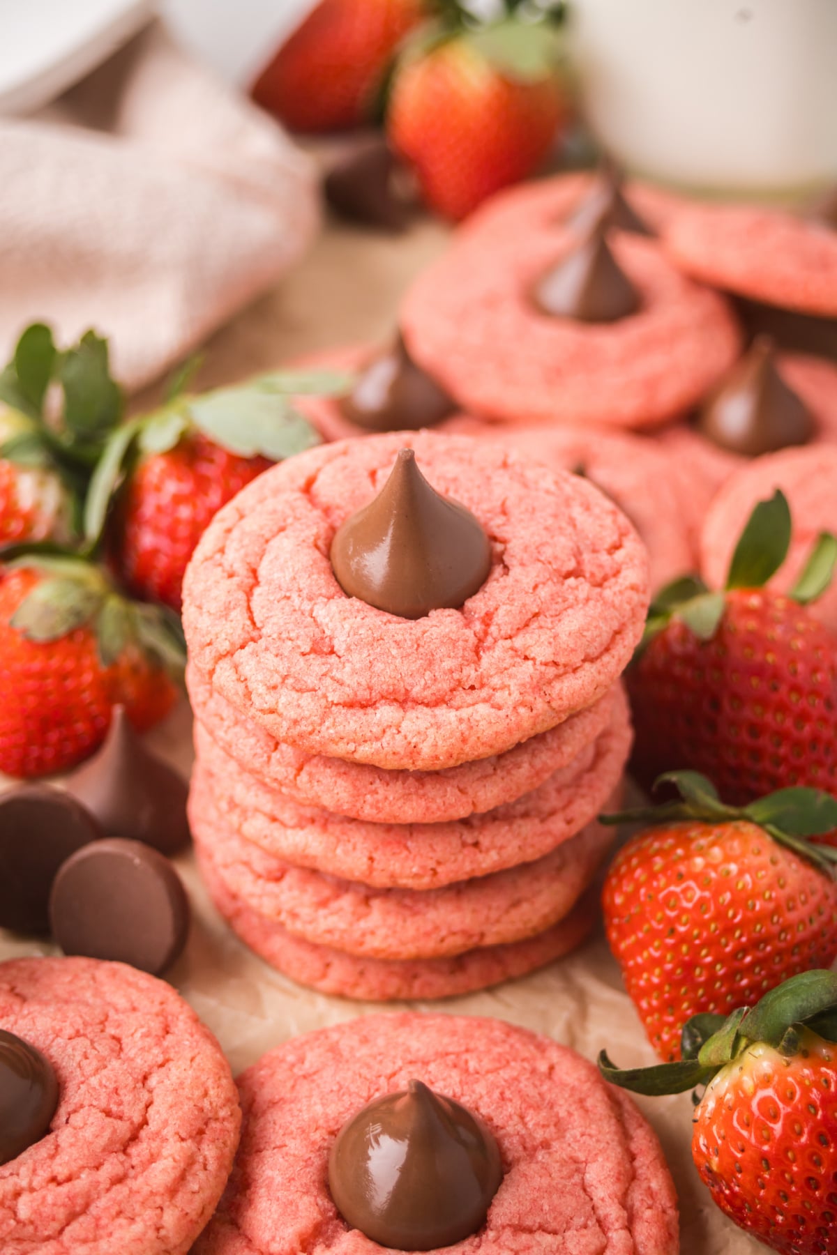 A stack of cookies on parcment covered table with strawberries 