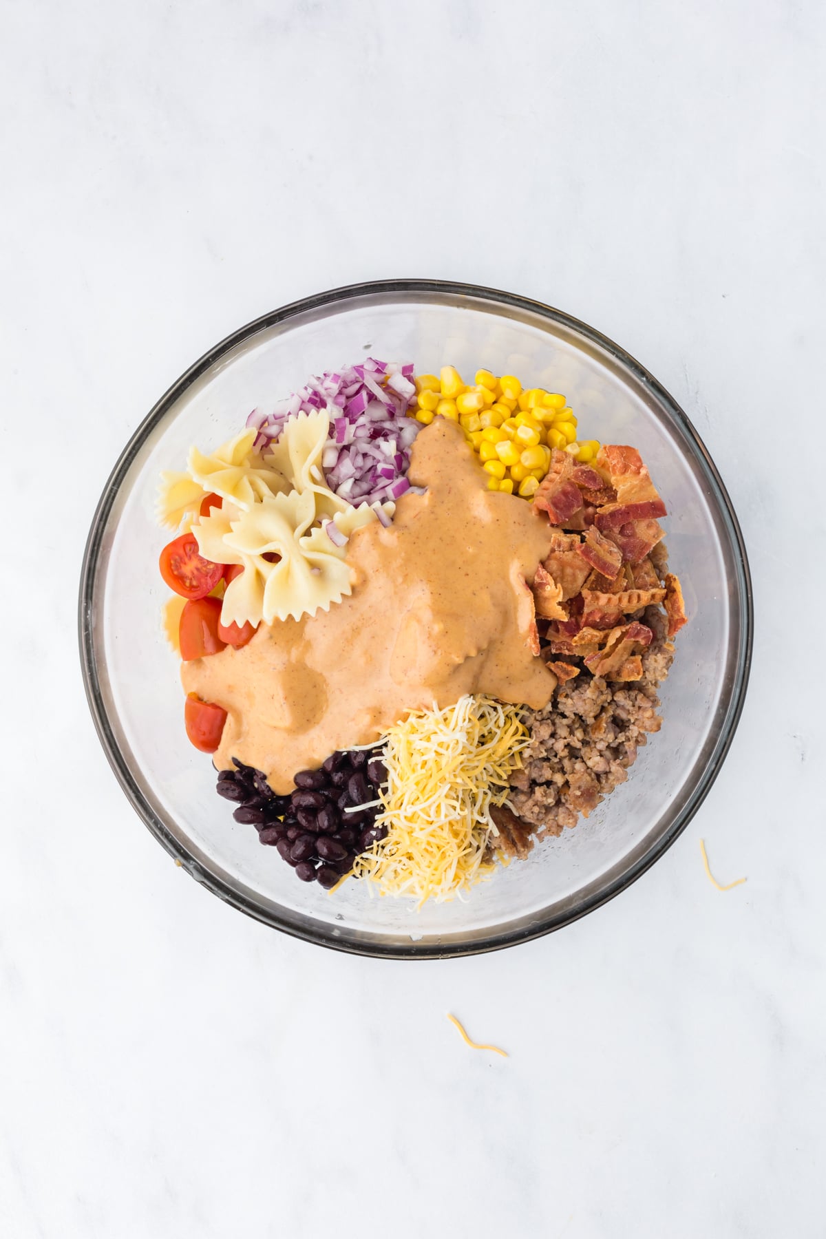 cowboy pasta salad ingredients being combined in large bowl