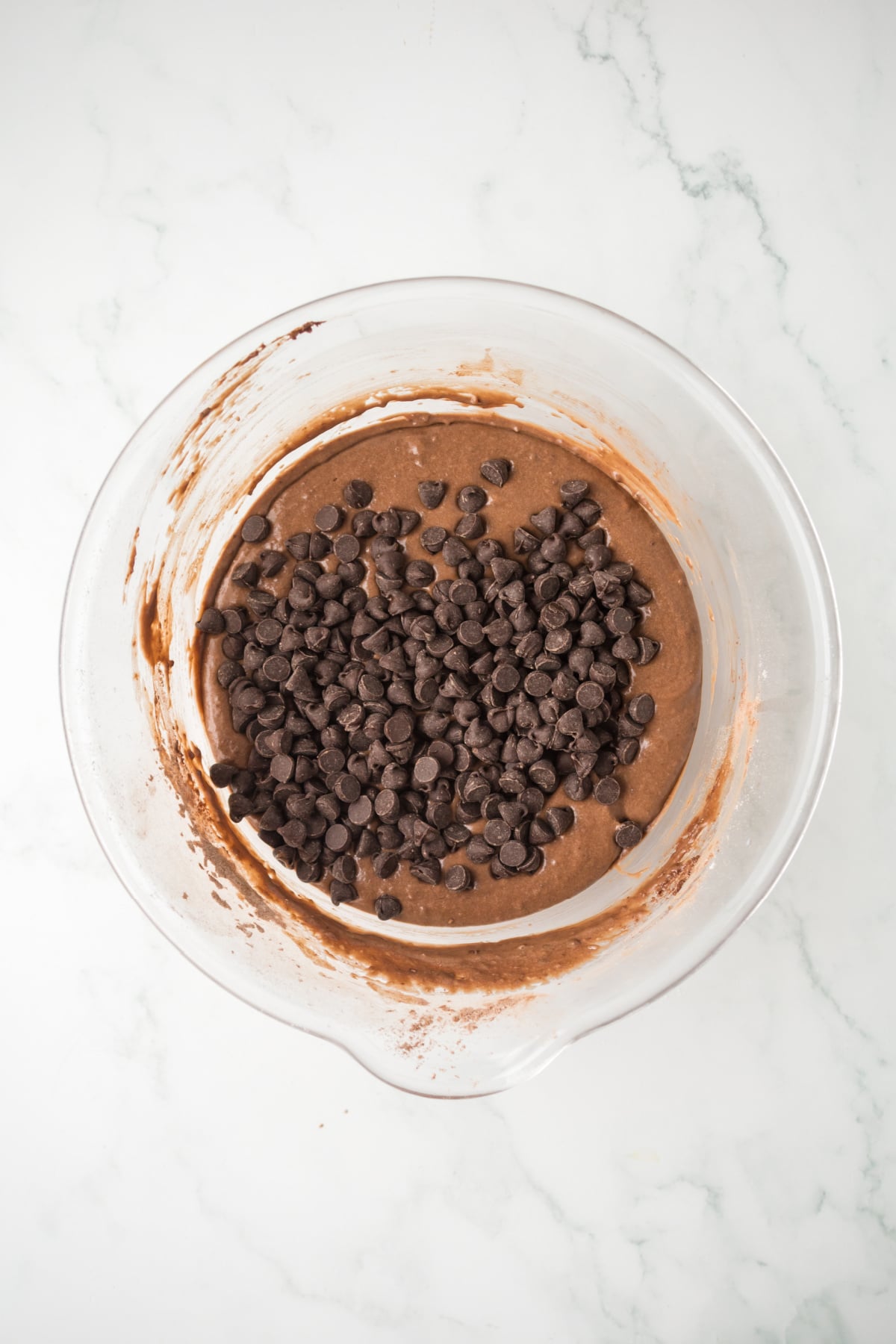 Folding chocolate chips in bowls into muffin batter for moist double chocolate chip muffins