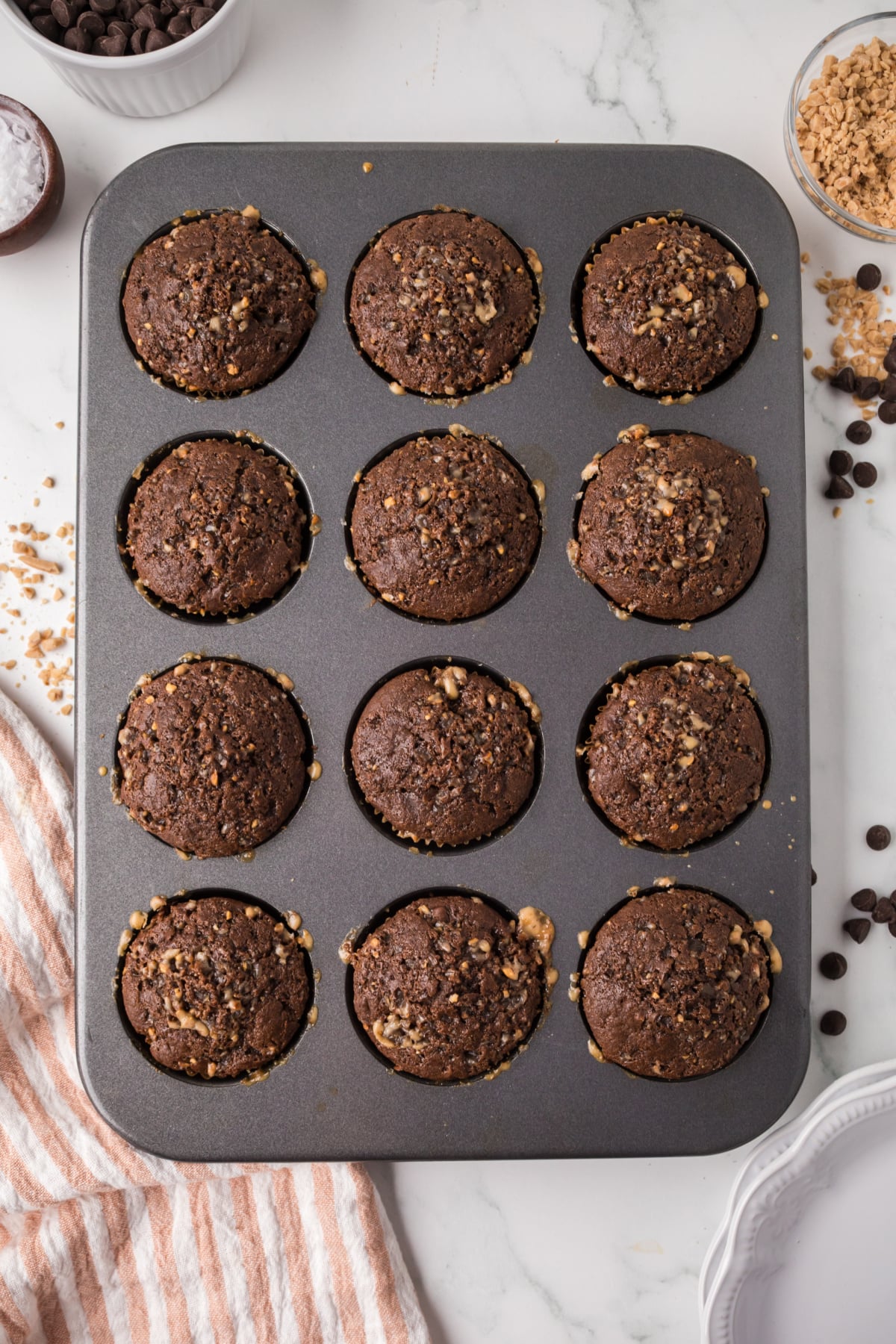 Filled muffin liners with chocolate bakery-style double chocolate chip muffins in a pan