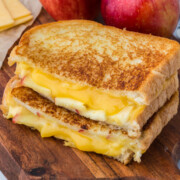 gouda grilled cheese sandwich with two halves on top of each other showing melted cheese and apple slices inside on cutting board