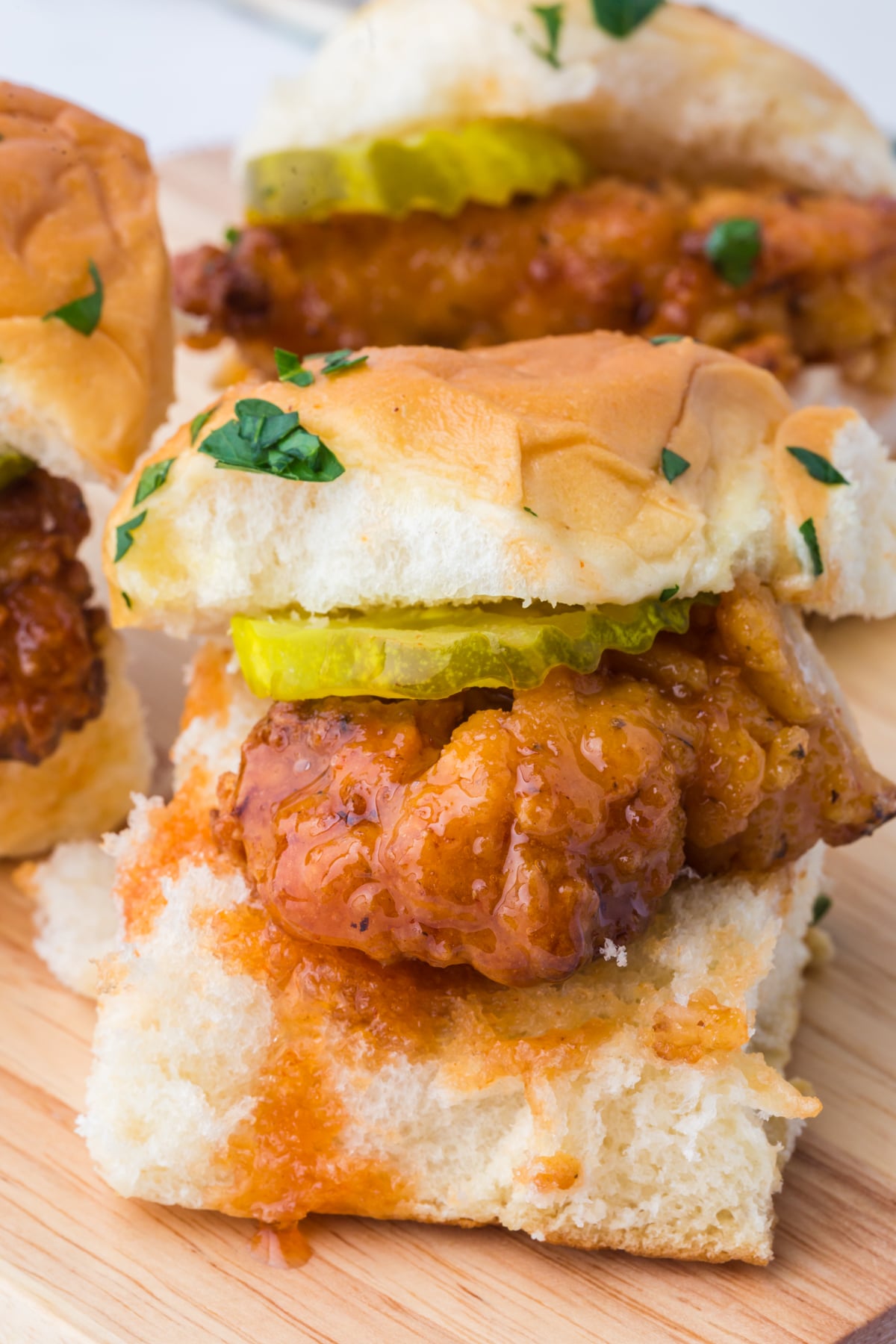 hot honey chicken sliders served on cutting board with crispy chicken and sauce