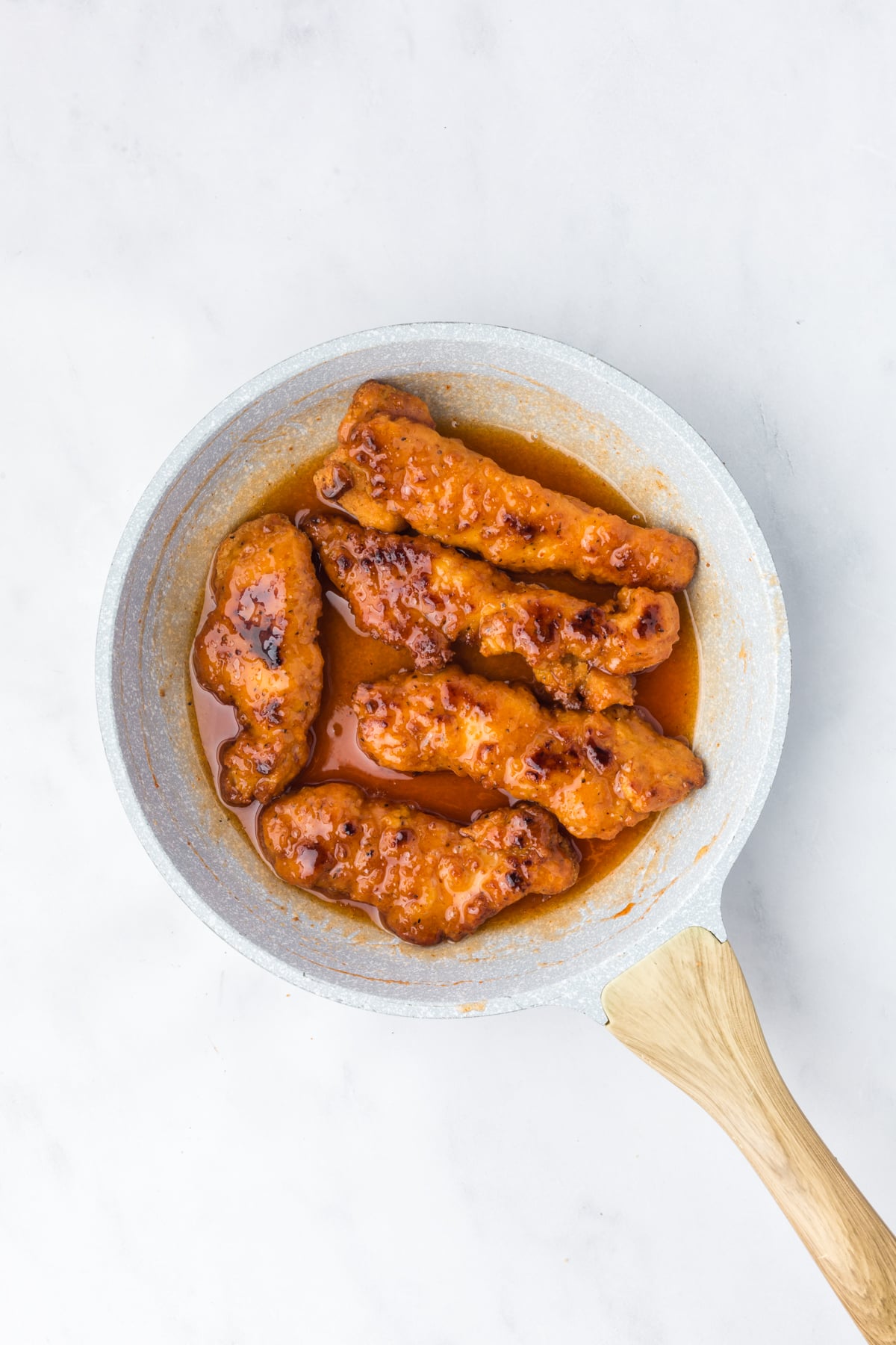 chicken tenders coated in hot honey sauce in skillet