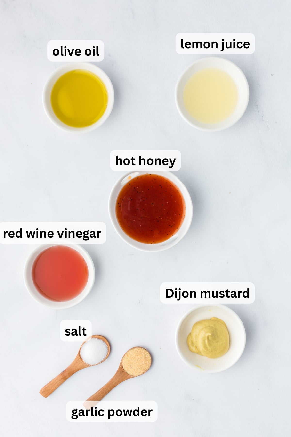 All of the ingredients needed to make hot honey vinaigrette in bowls on table