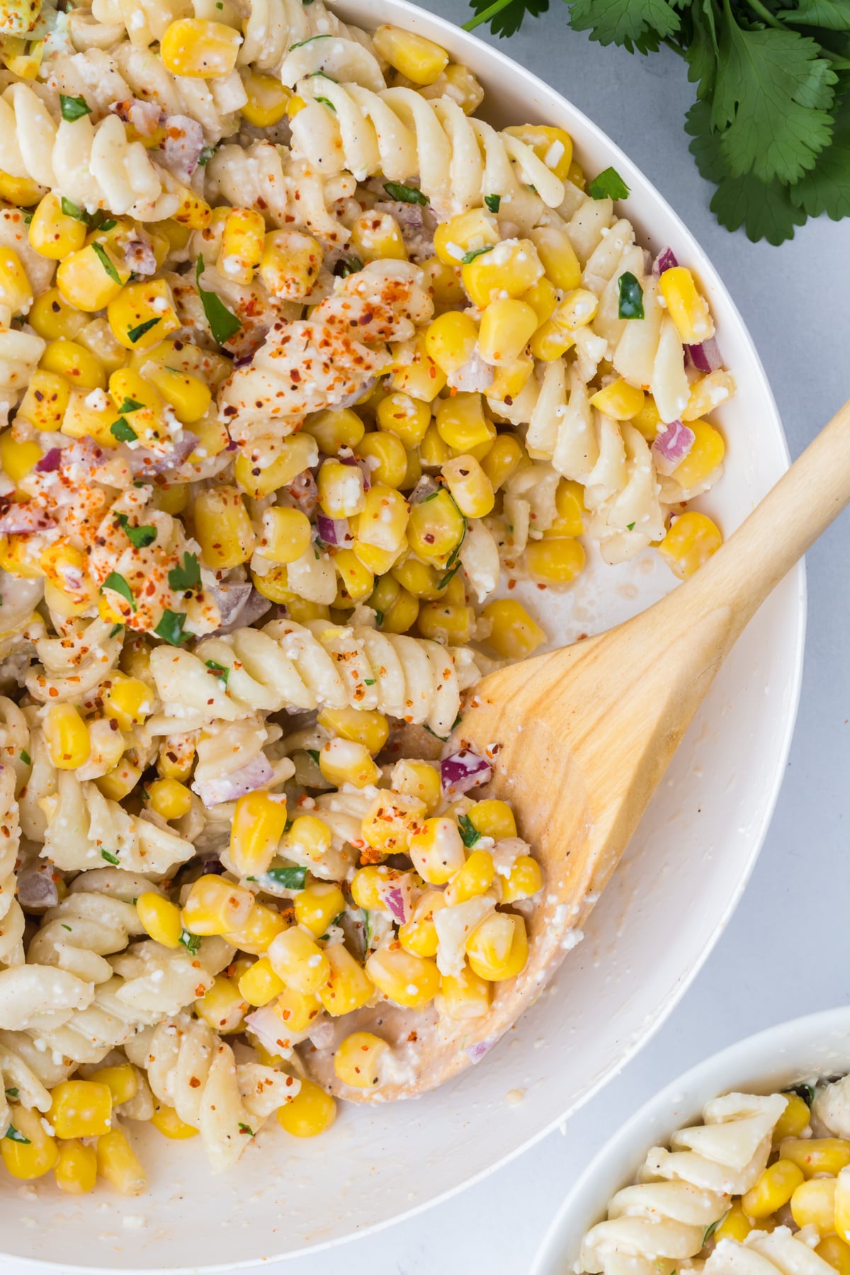 pasta salad served in bowl as bbq side dish with wooden spoon