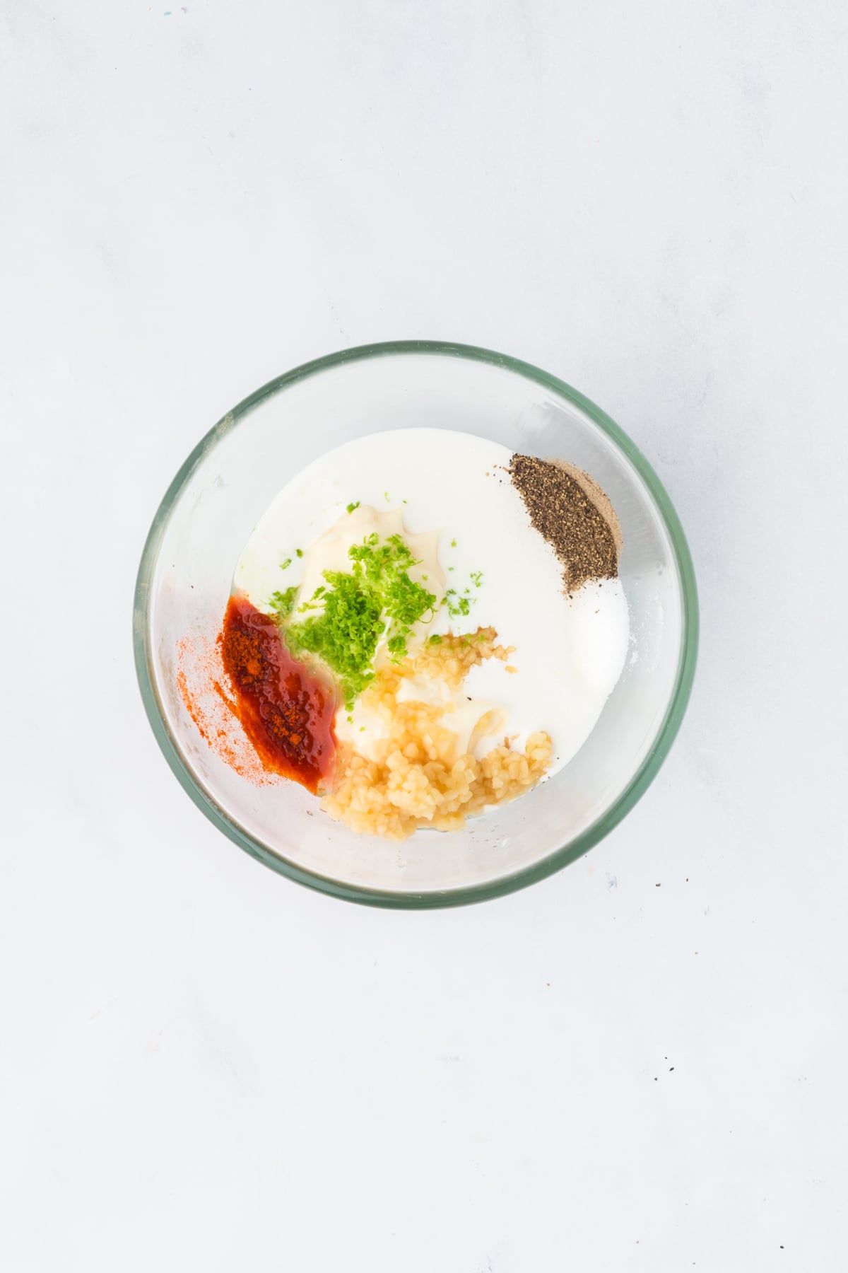 creamy dressing ingredients in bowl with mayo crema lime and spices for pasta salad