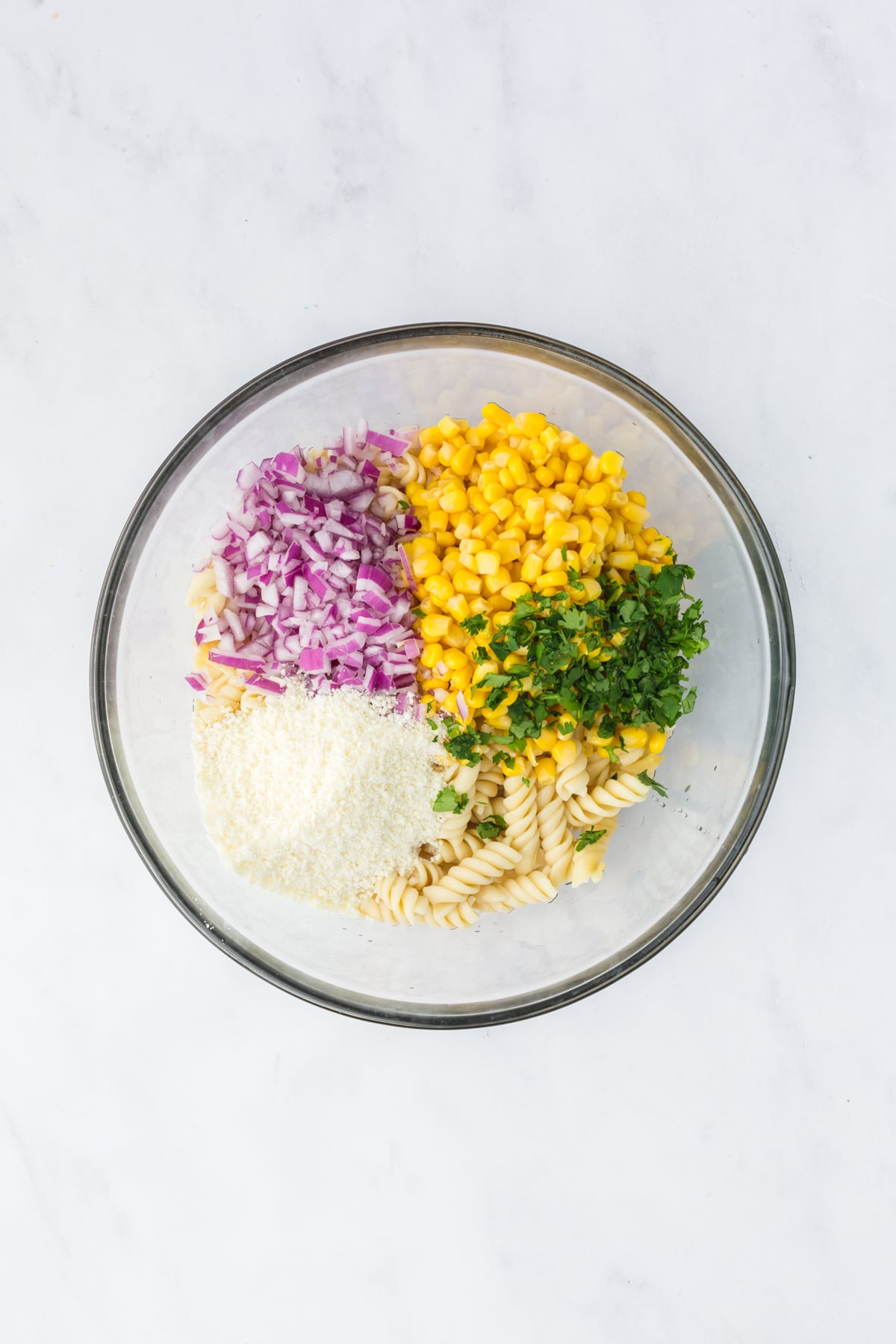 combining pasta corn onion cheese and more in large bowl