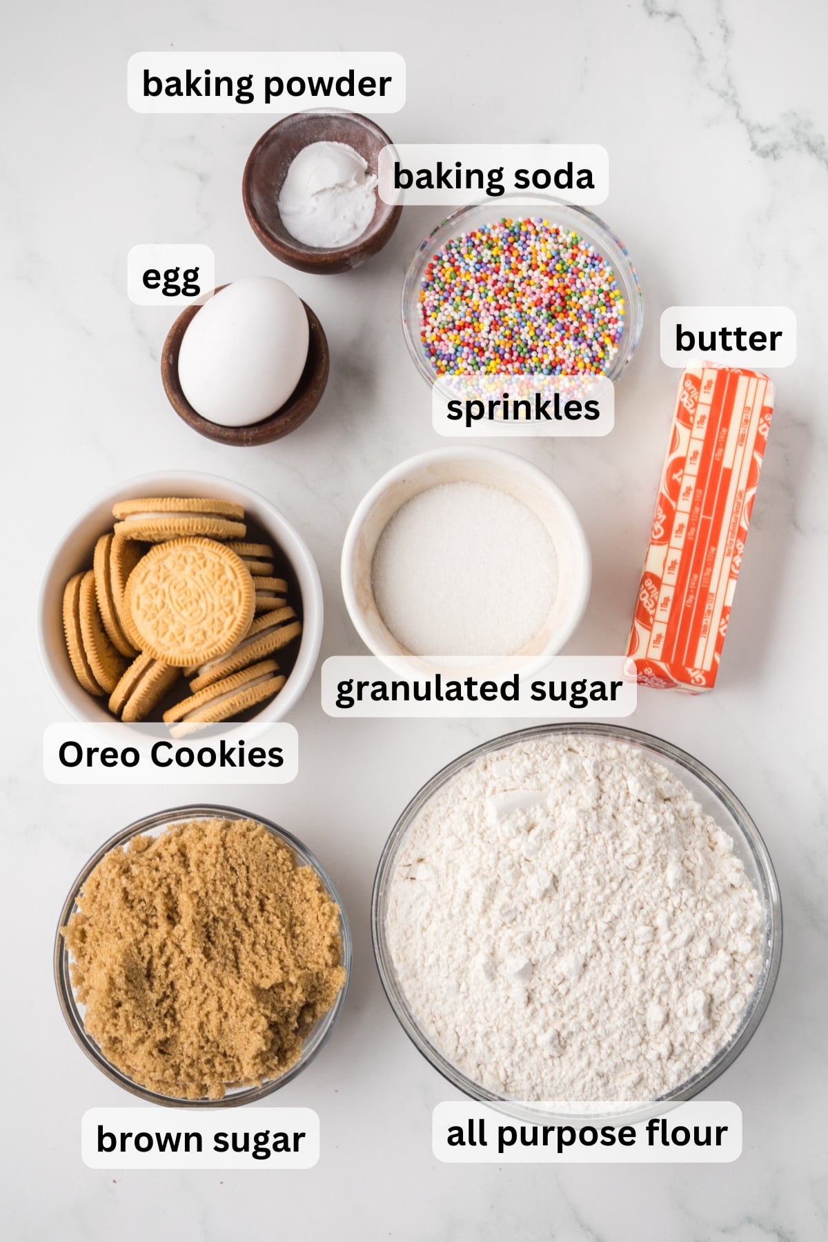 ingredients for oreo cookie bars including butter sugar flour and golden oreos in bowls on counter.