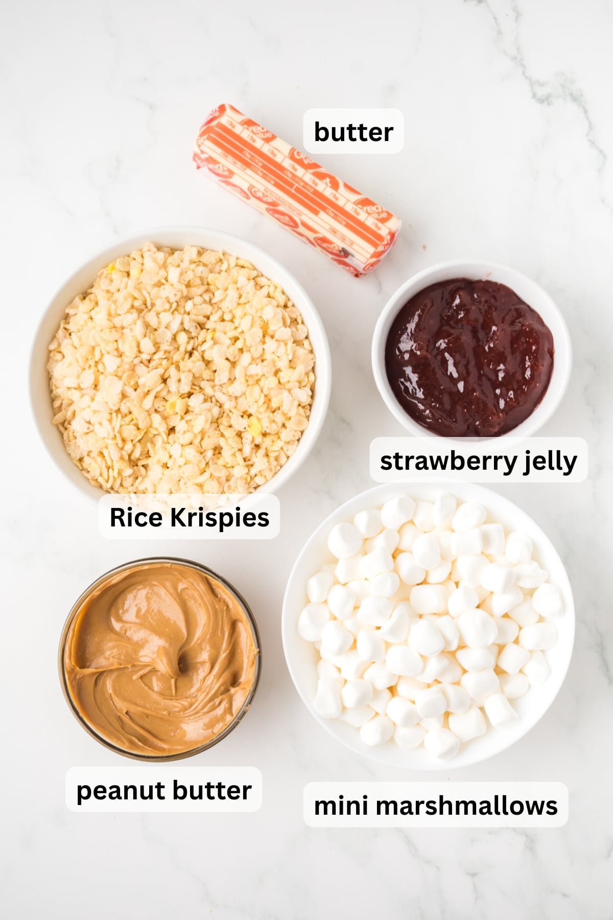 ingredients for peanut butter jelly rice krispie treats including marshmallows peanut butter cereal and jelly in bowls on a table.